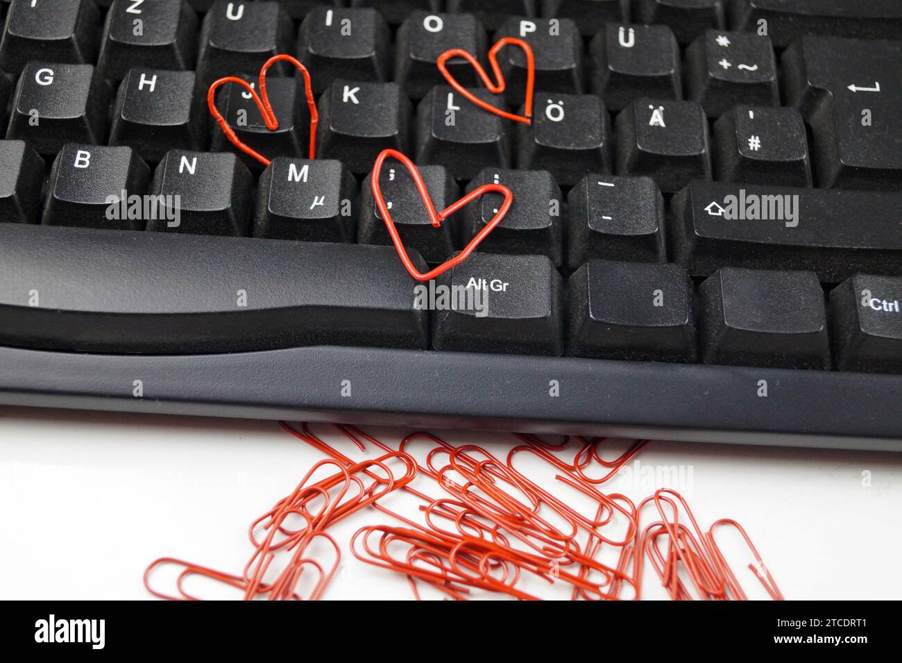 clavier avec trombones rouges, trois d'entre eux en forme de coeur, amour dans le bureau Banque D'Images