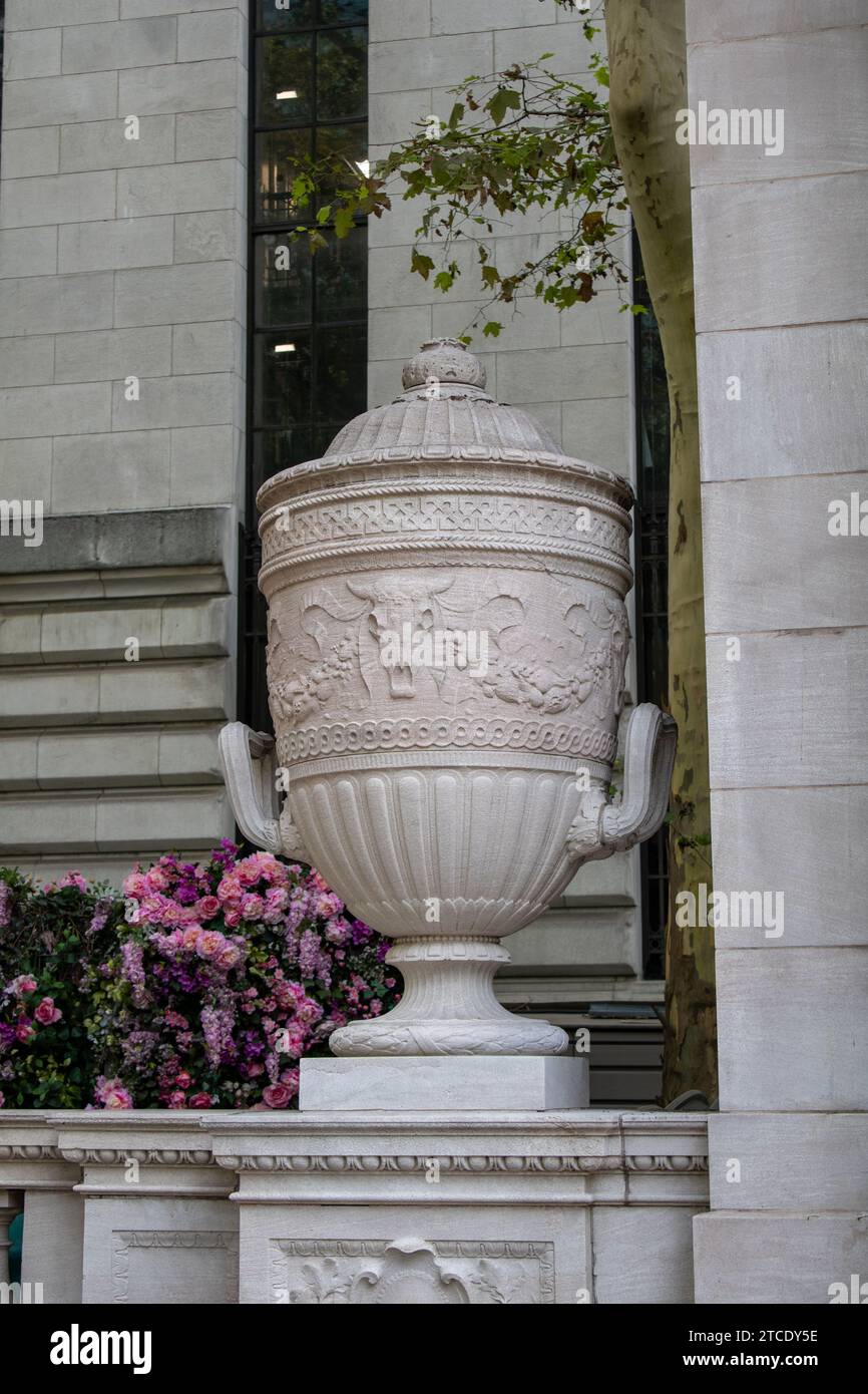 Un grand vase décoratif est situé à côté des marches d'un imposant immeuble de bureaux, apportant une touche d'élégance à l'entrée Banque D'Images