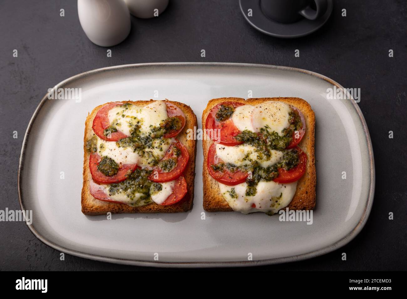 Toast avec fromage mozzarella, tomates et sauce pesto. Petit déjeuner chaud cuit au four avec une tasse de café. Plat traditionnel, cuisine maison. Selectiv Banque D'Images