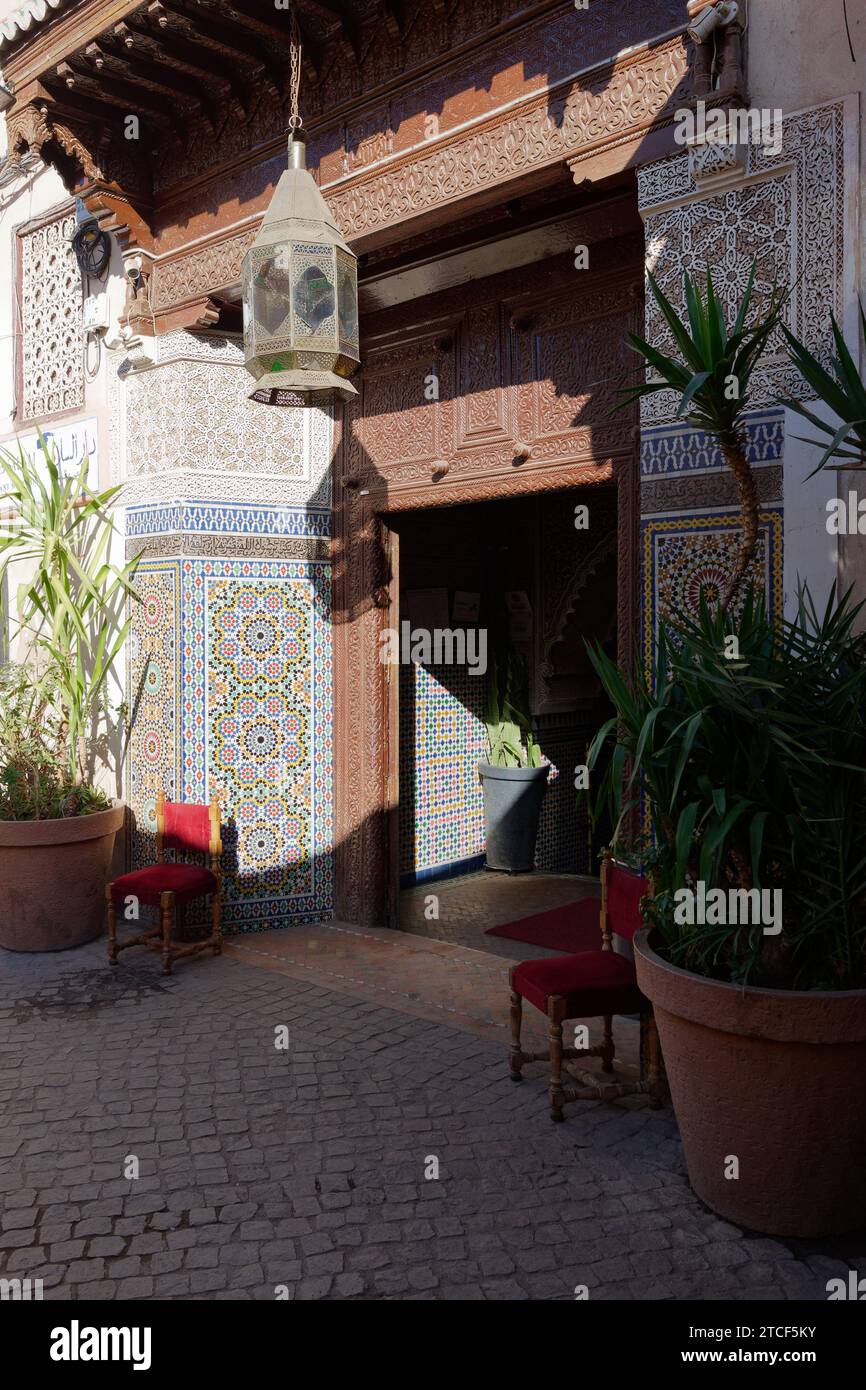 Porte ornée de formes géométriques et entourage en bois entouré de pots de plantes dans la ville de Marrakech aka Marrakech, Maroc, 12 décembre 2023 Banque D'Images