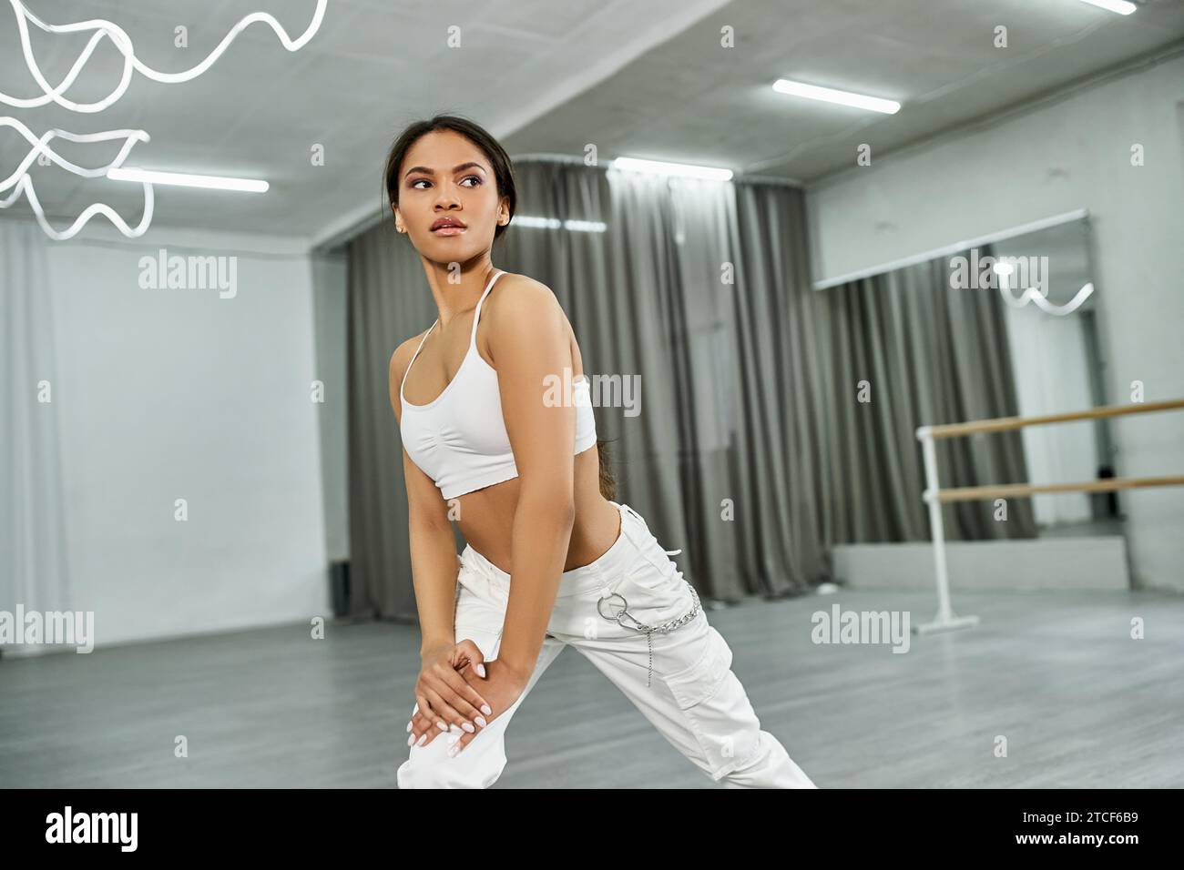 danseur afro-américain professionnel en vêtements de sport blancs répétant et pratiquant dans la salle de danse Banque D'Images