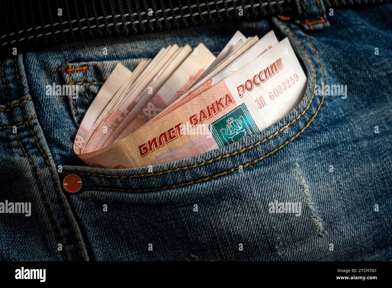 De l'argent dans la poche d'un Jean bleu. grande bourre de billets russes de mille roubles ou de billets dépasse de la poche de jeans bleus. Banque D'Images