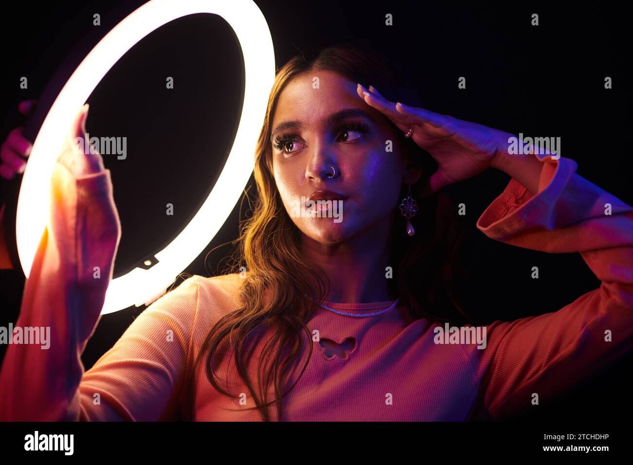 Jeune femme avec le perçage du nez posant sous la lumière annulaire Banque D'Images