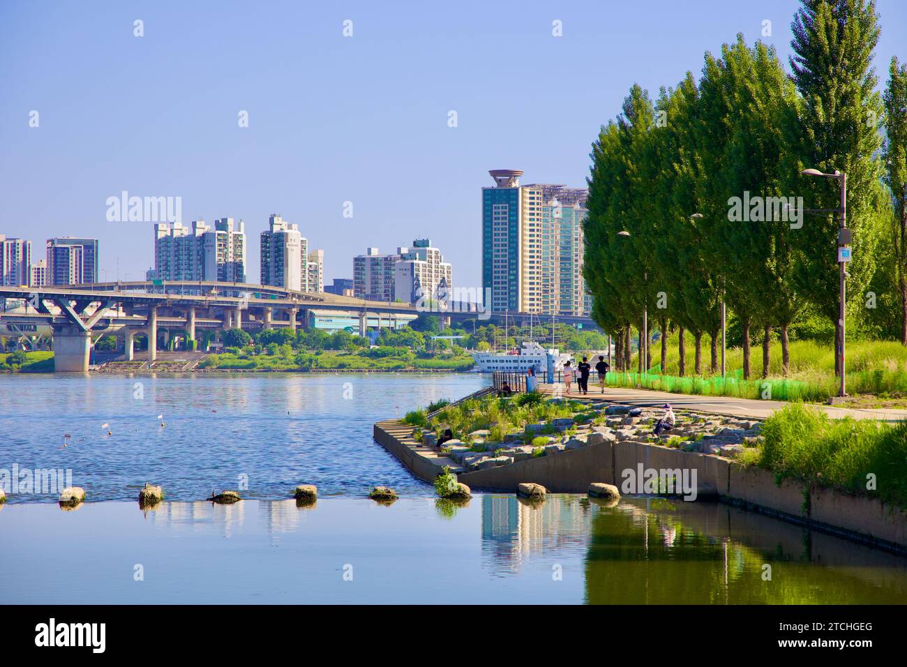 Séoul, Corée du Sud - 2 juin 2023 : une représentation sereine des eaux calmes de Tan Stream avant de rejoindre la rivière Han, avec des adeptes du parc sur les chemins le long de l'emb Banque D'Images