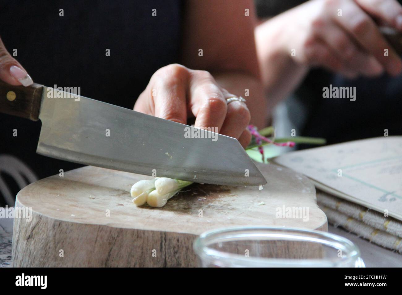 Gros plan d'une personne coupant des oignons sur une table en bois. Banque D'Images