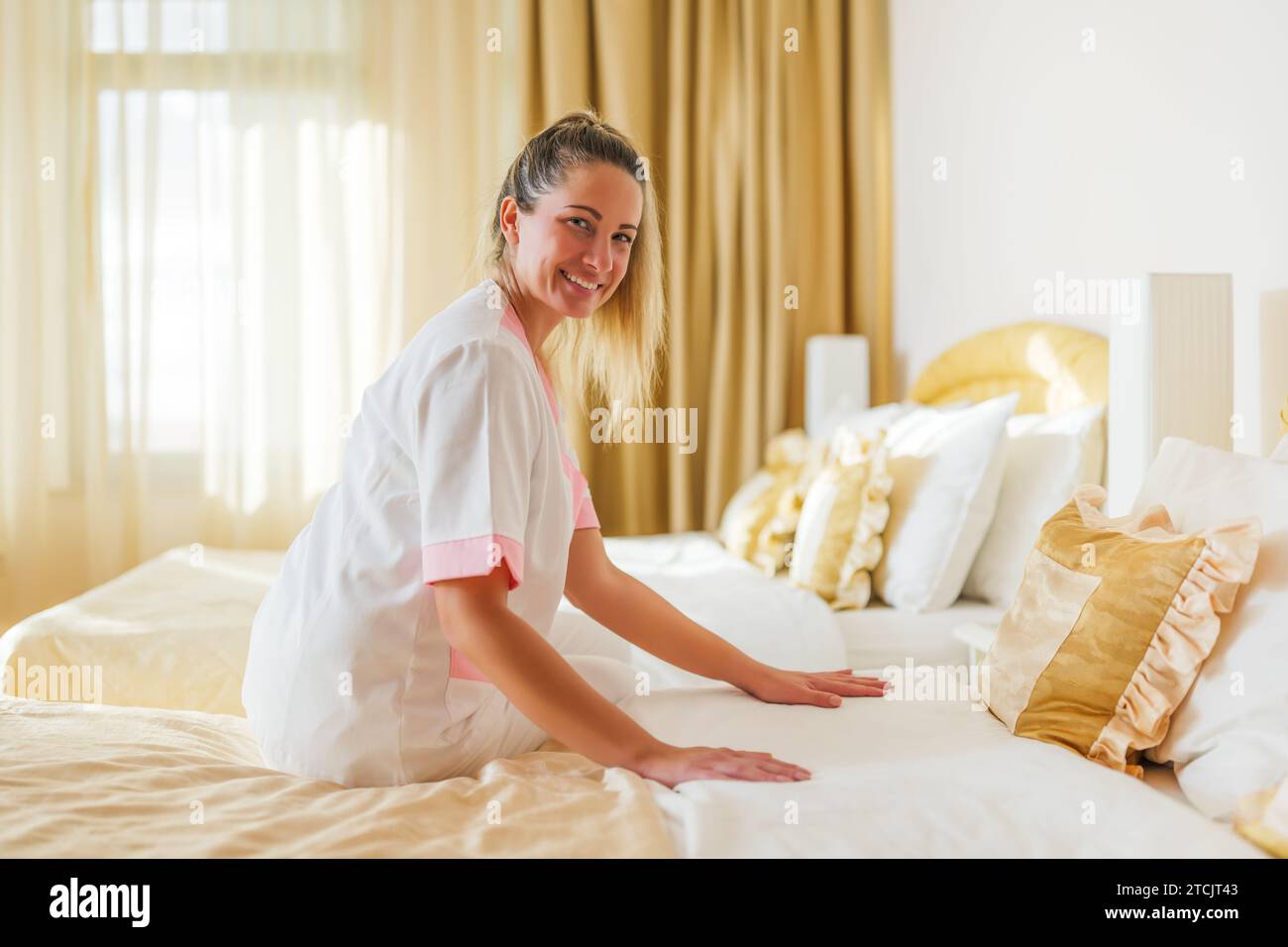 Belle femme de chambre faisant le lit dans une chambre. Banque D'Images