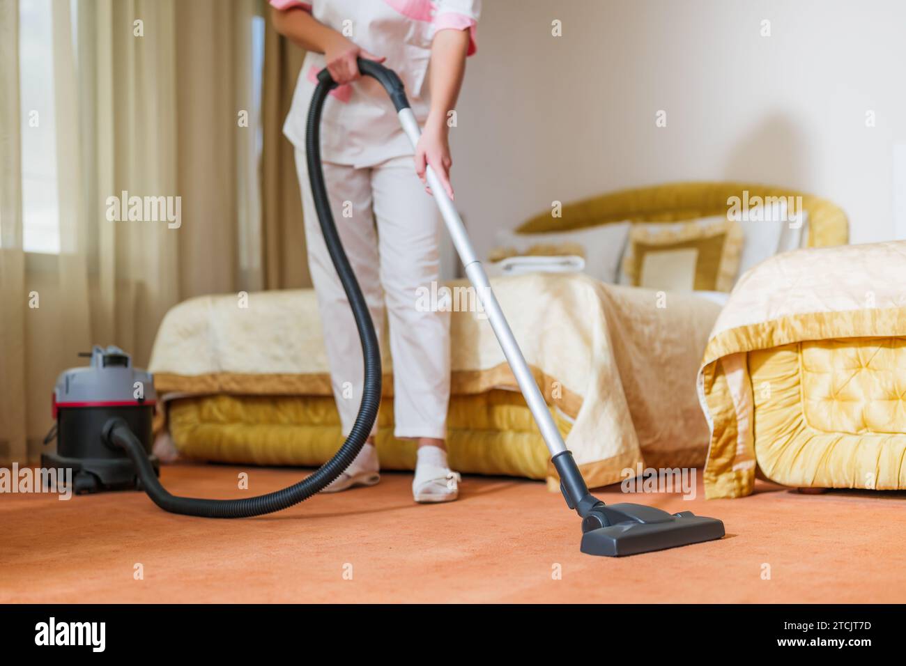 Image rapprochée de la chambre de la femme de ménage de l'hôtel qui passe l'aspirateur. Banque D'Images