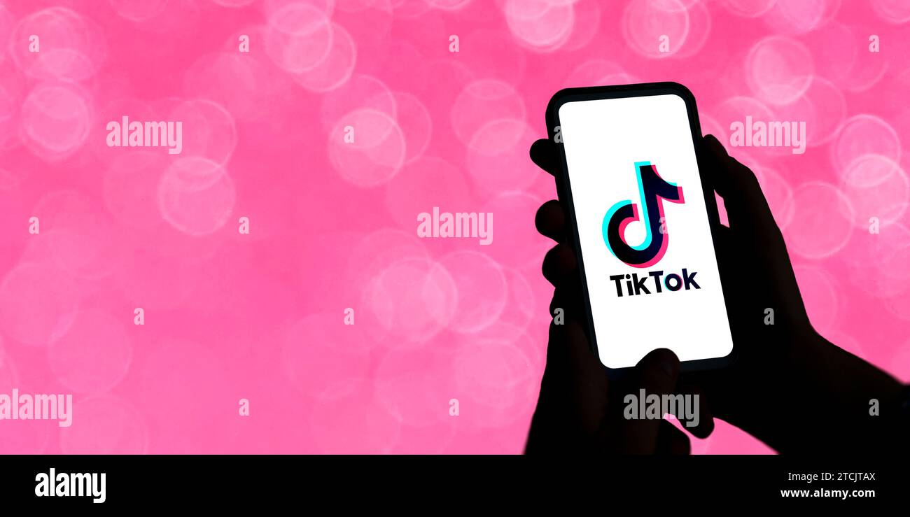 Femme tenant un téléphone portable avec le logo Tiktok à l'écran. Divertissement court réseau social vidéo. Illustration avec concept adolescent. Contraste élevé Banque D'Images