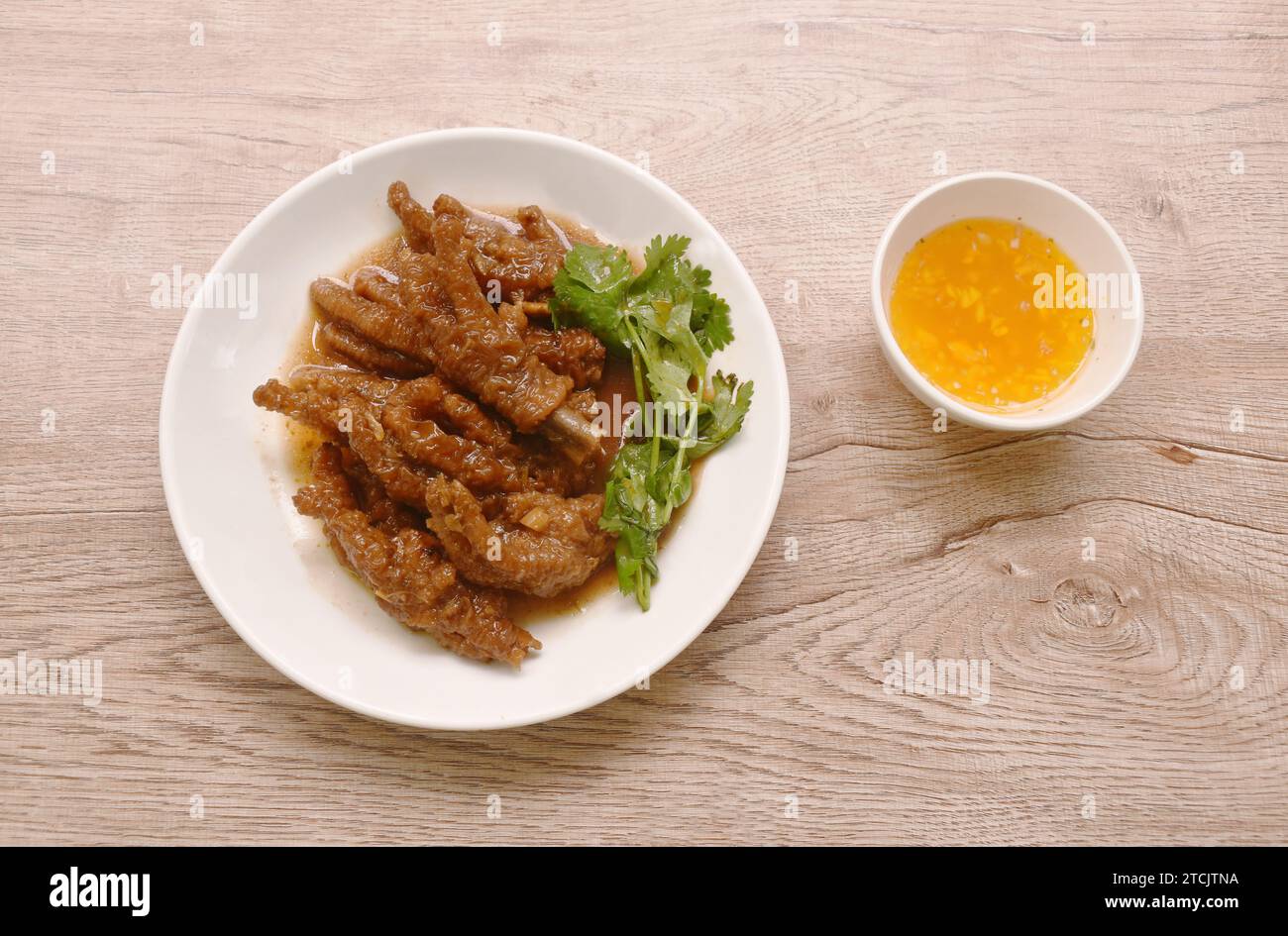 pied de poulet cuit à la vapeur dans une sauce de soja rouge sucrée sur une assiette trempant de la sauce chili Banque D'Images