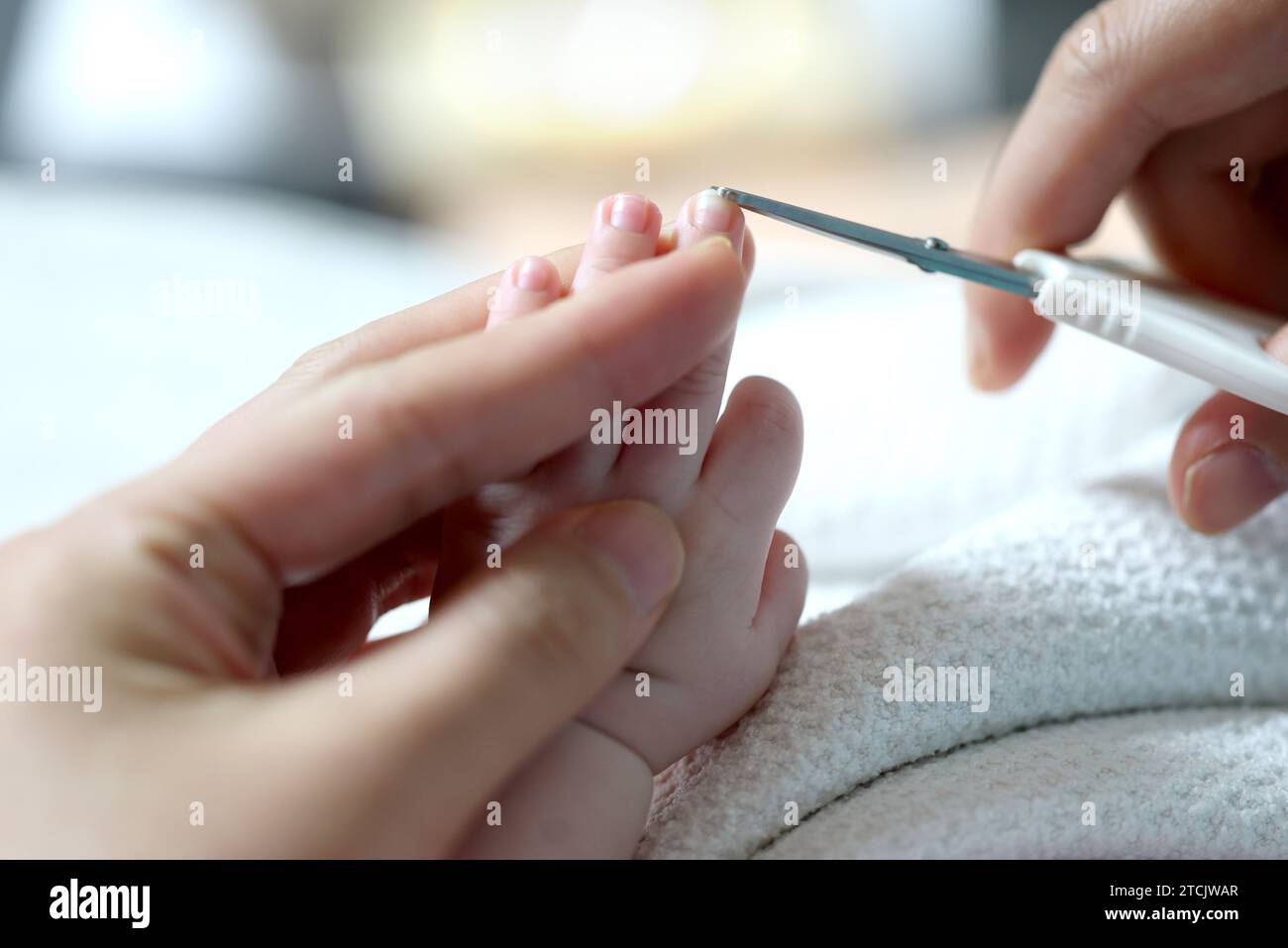 Les mains de la mère coupant les ongles du nouveau-né avec des ciseaux Banque D'Images