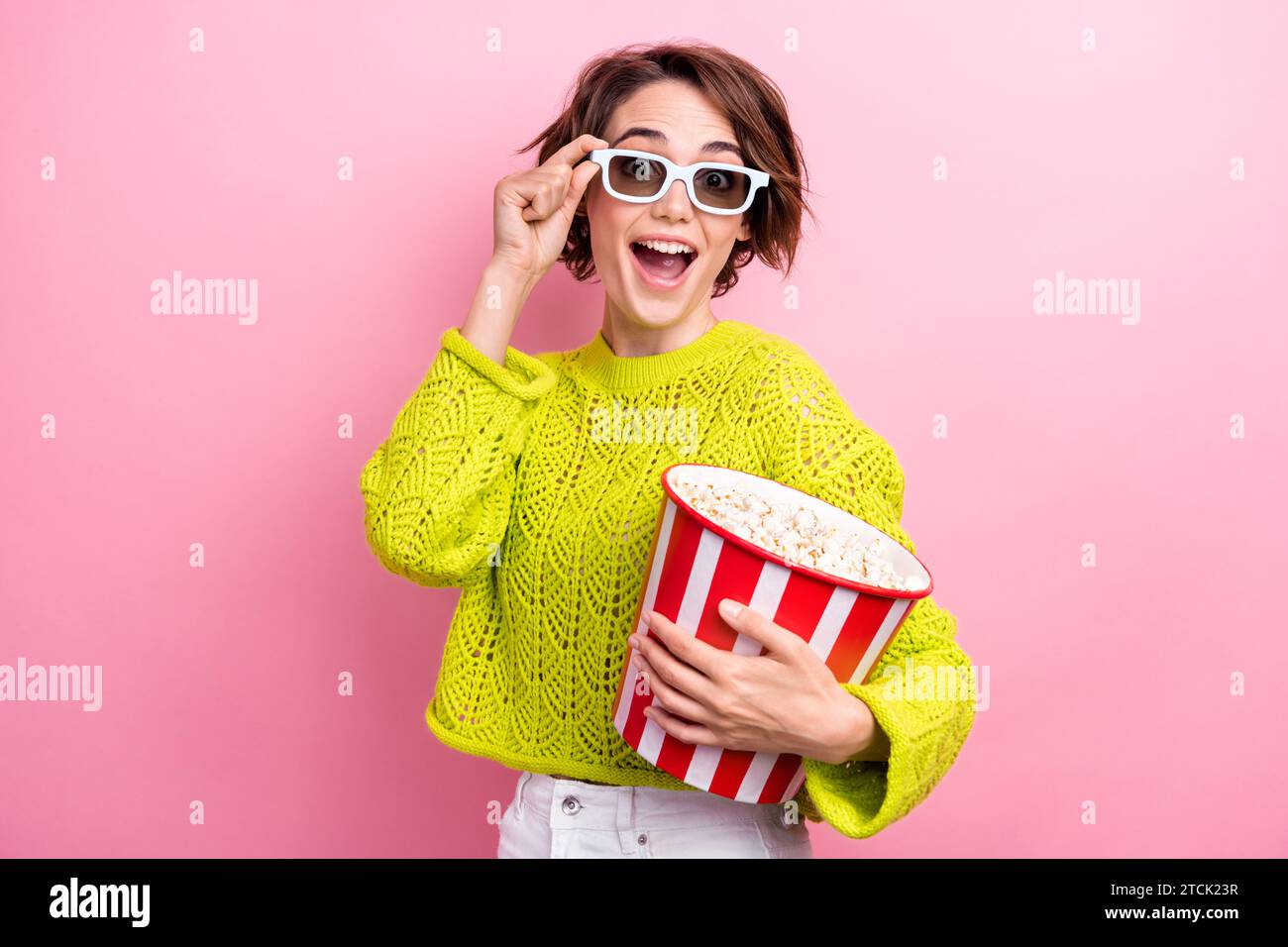 Photo de fille aime regarder des films de première qualité préférés divertissement lunettes tactiles tenir le seau pop-corn isolé sur fond de couleur rose Banque D'Images
