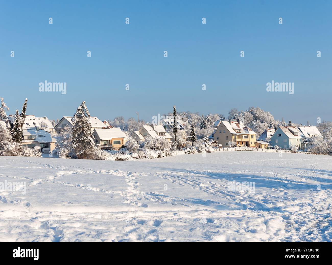 Bel hiver dans un village européen - vue sur un champ enneigé avec en toile de fond des maisons de campagne. Allemagne Banque D'Images