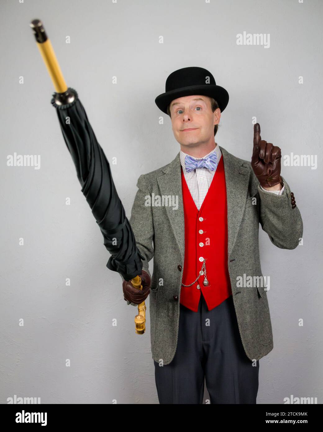 Portrait de Vintage British Gentleman en tweed Jacket et Red Waistcoat tenant un parapluie s'efforçant d'attirer l'attention. Banque D'Images