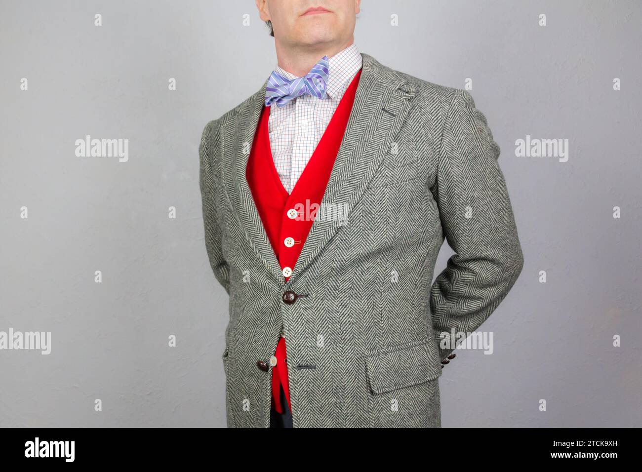 Portrait d'élégant gentleman en tweed veste et gilet ou gilet rouge vif debout avec les mains derrière le dos. Style vintage et mode rétro. Banque D'Images