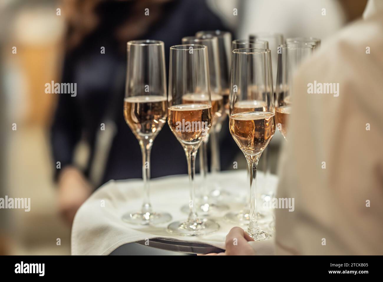 Un jeune serveur tient une assiette avec du champagne ou du prosecco comme boisson de bienvenue lors d'un événement à l'hôtel. Banque D'Images