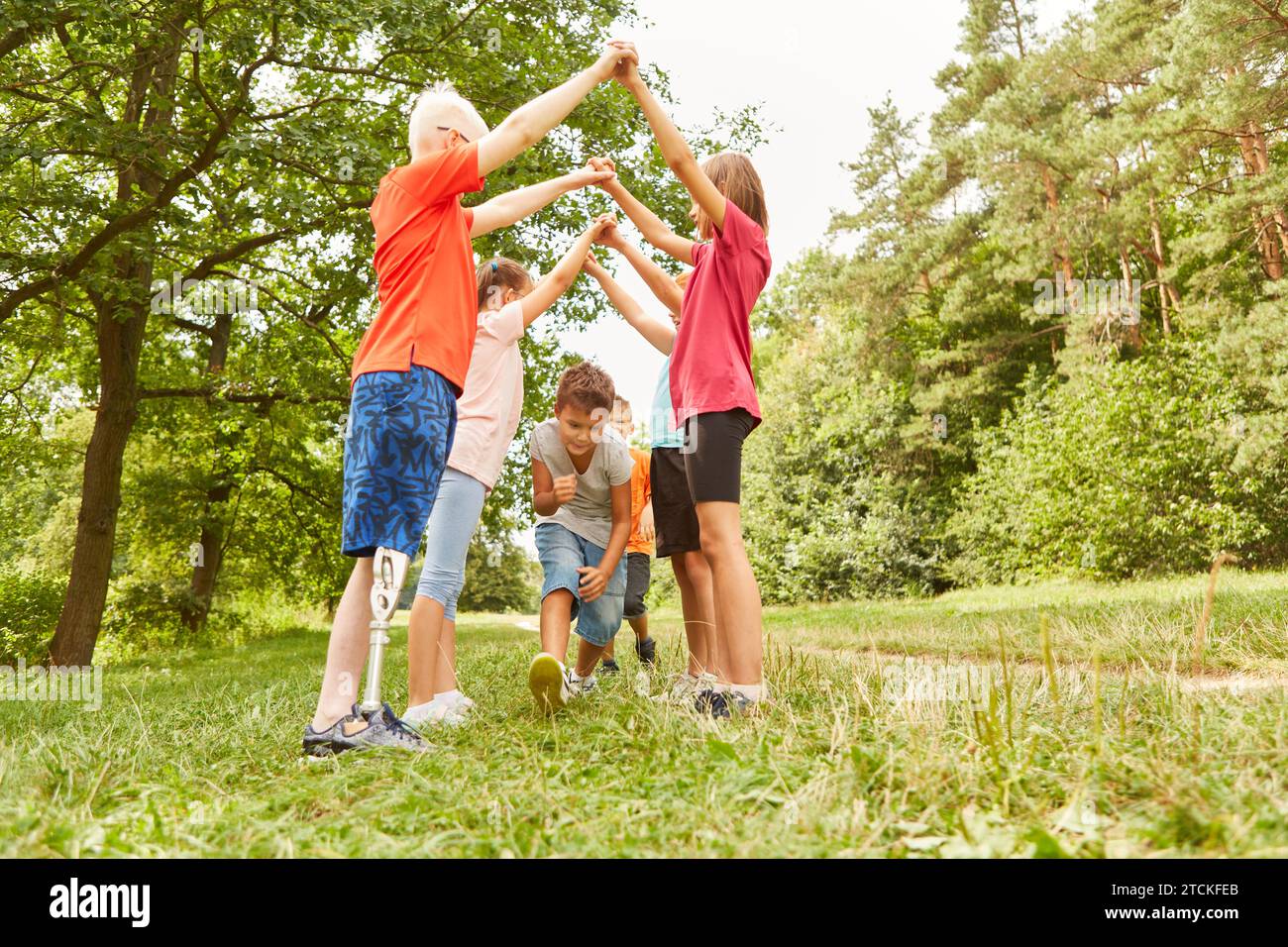 Groupe d'enfants à la fête d'anniversaire en plein air jouant à des jeux en été Banque D'Images