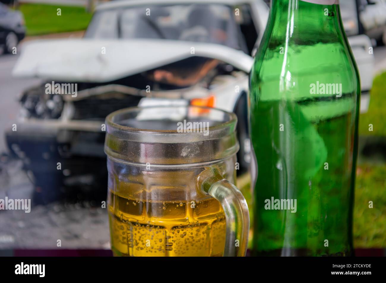 Un concept de conduite avec une pinte et des bouteilles de bière et une photo d'une voiture écrasée en arrière-plan. Banque D'Images