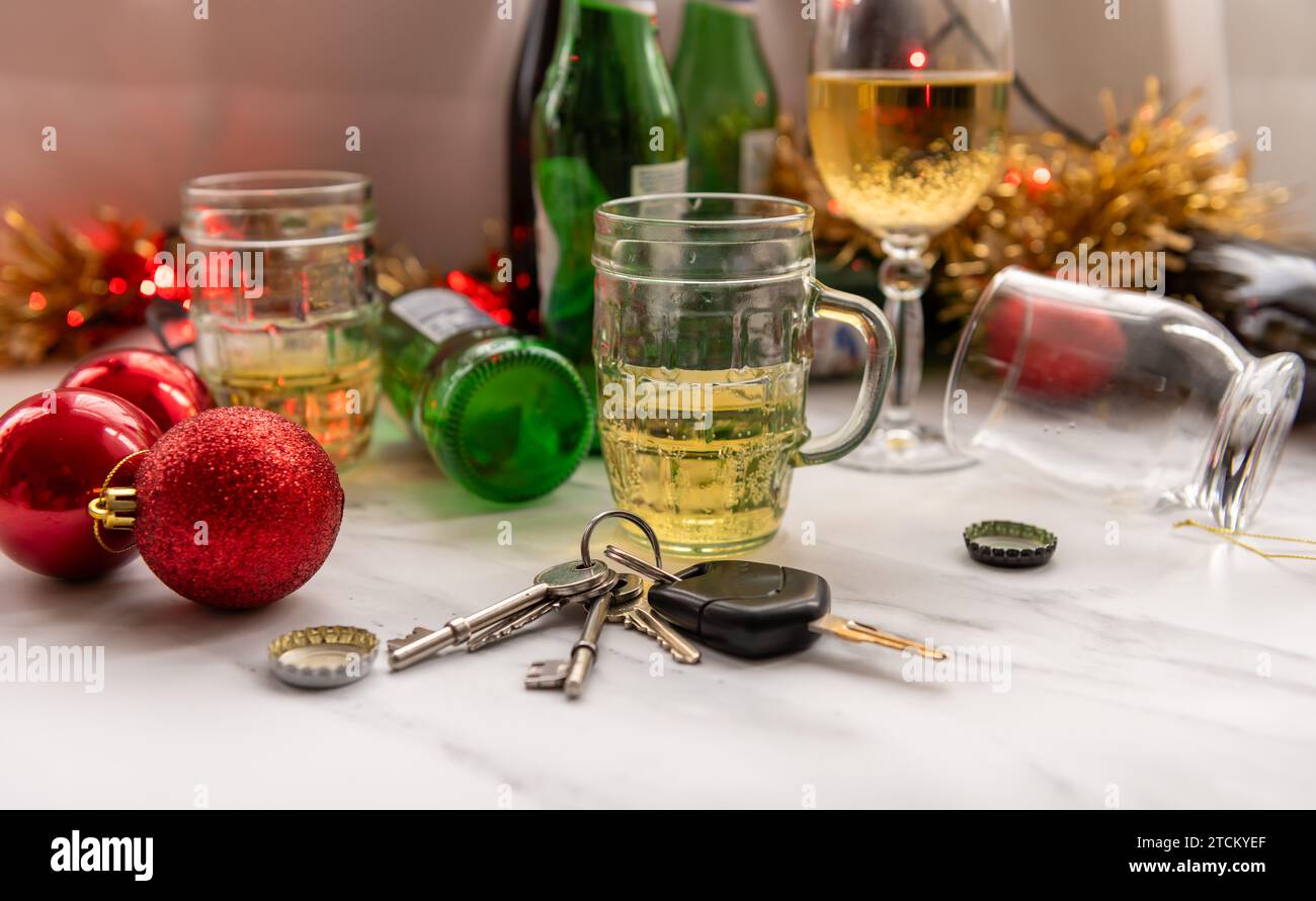Un concept de conduite de Noël et de fête avec un jeu de clés de voiture sur une table pleine de boissons alcoolisées et de décorations. Banque D'Images