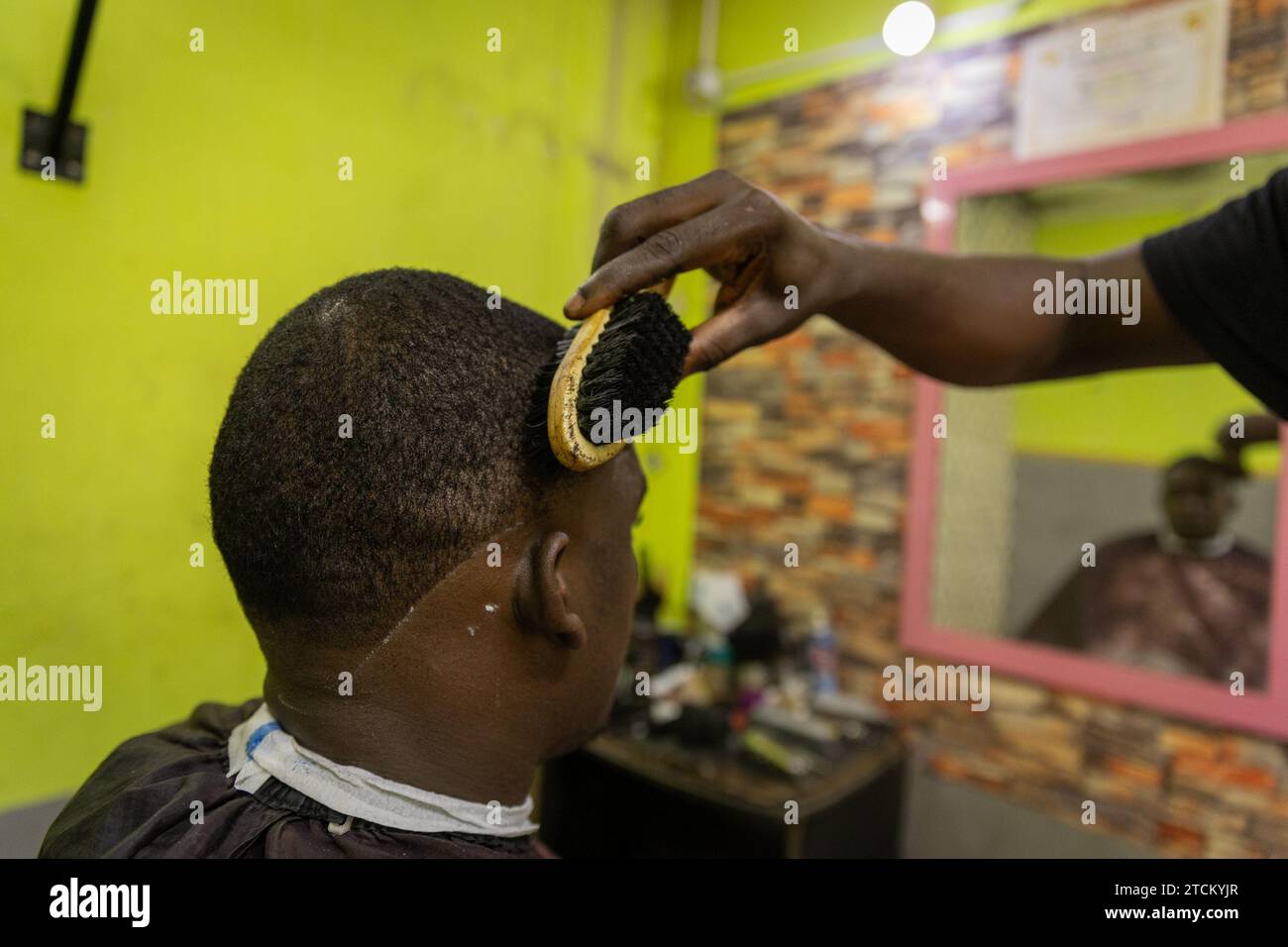 Un barbier brosse les cheveux de son client pendant une coupe de cheveux. Banque D'Images