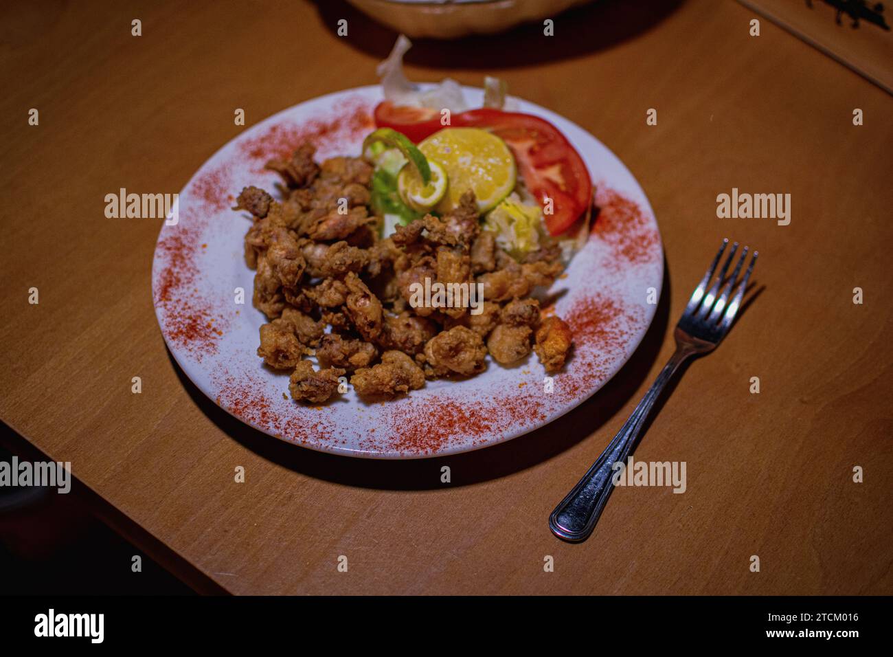 REPAS TYPIQUE ESPAGNOL CHOPITOS AVEC DES LÉGUMES D'ACCOMPAGNEMENT DANS UN DÉCOR SUR UNE TABLE EN BOIS AVEC UNE FOURCHETTE SUR LE CÔTÉ Banque D'Images