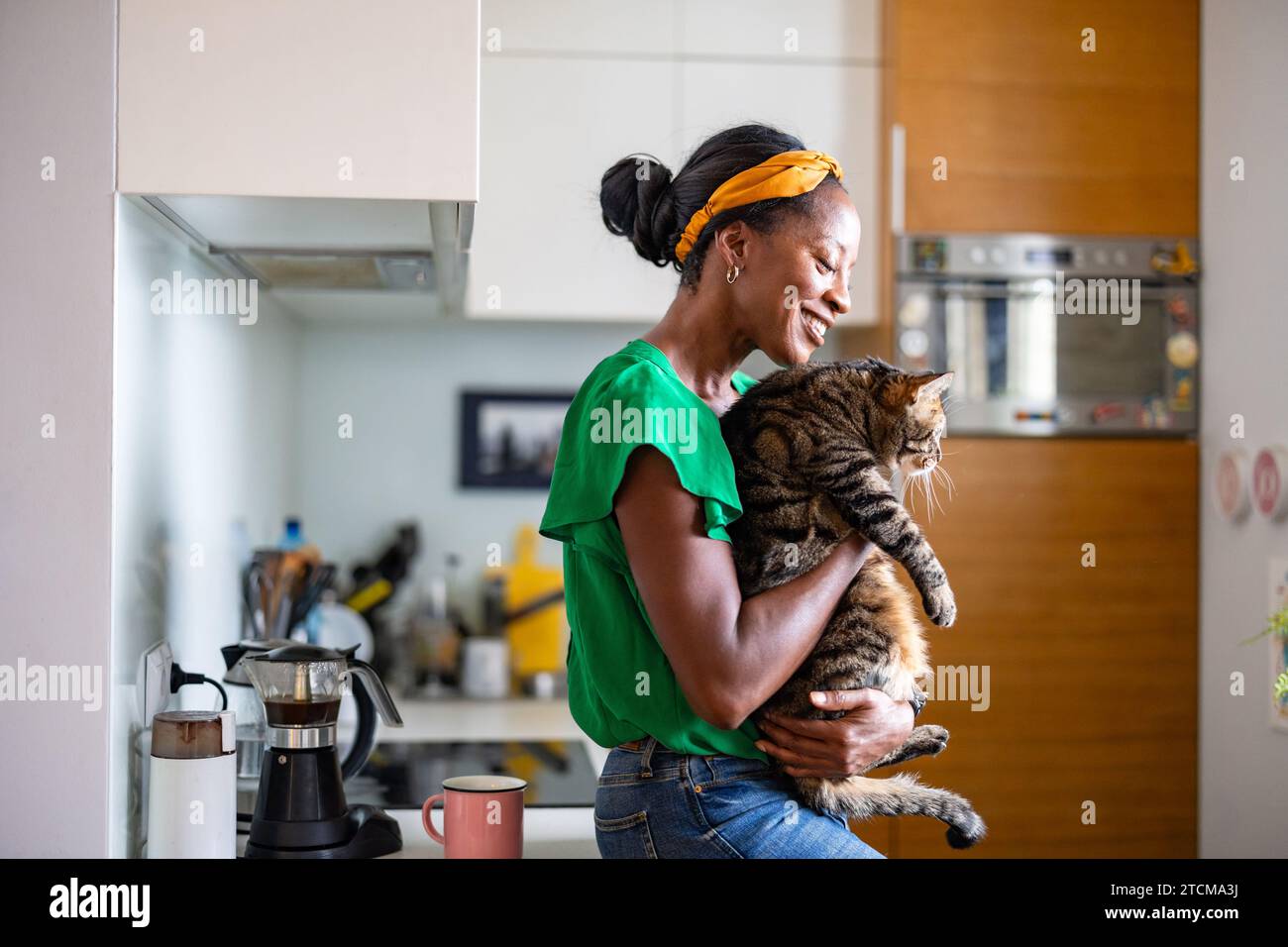 Femme souriante tenant son chat à la maison Banque D'Images