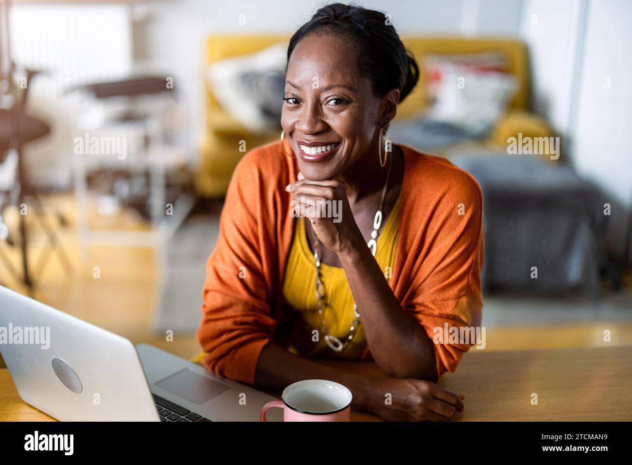Smiling woman working on laptop at home Banque D'Images