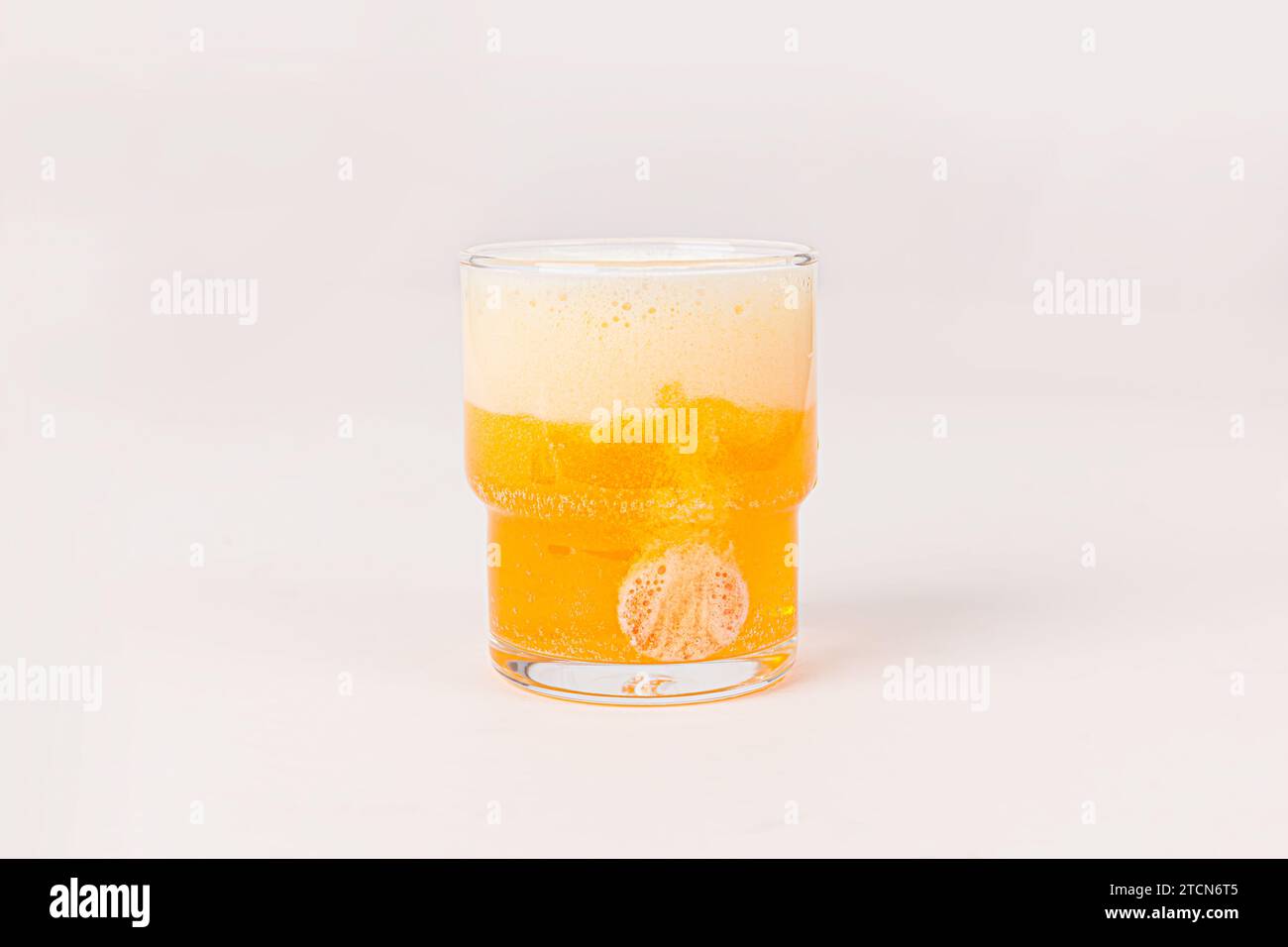 Comprimé effervescent orange de vitamine C a chuté et se dissoudre dans un verre d'eau avec des bulles isolées sur fond blanc Banque D'Images
