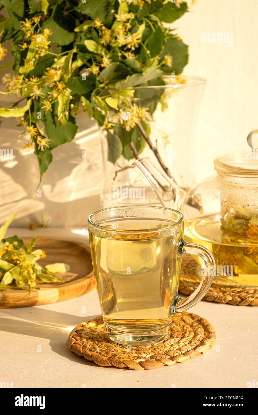 Thé de fleur de Linden dans la tasse en verre transparent avec cuillère à thé sur un fond Banque D'Images