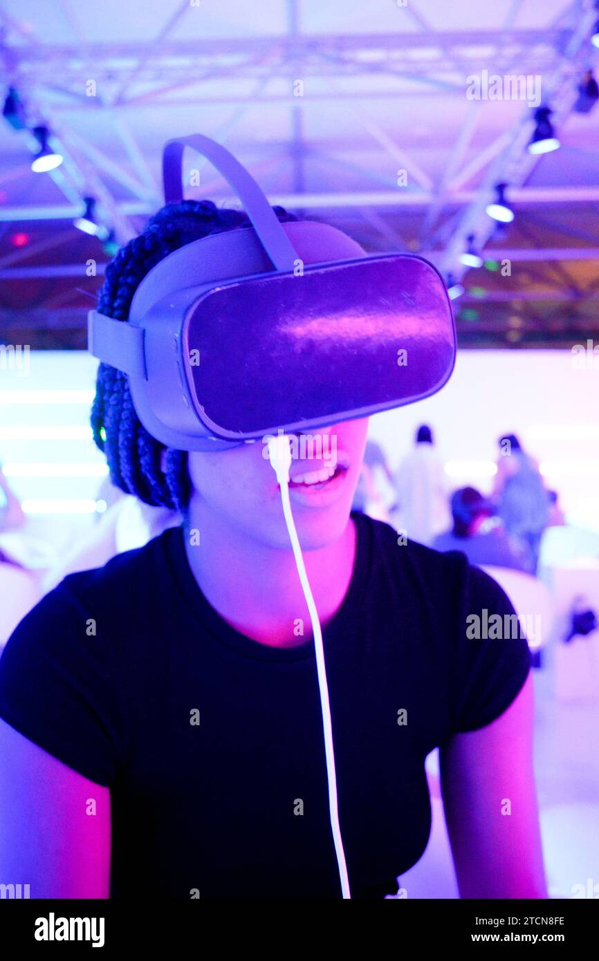 Fille avec tresses portant des lunettes VR de réalité virtuelle avec fond de lumières de néon vertical Banque D'Images
