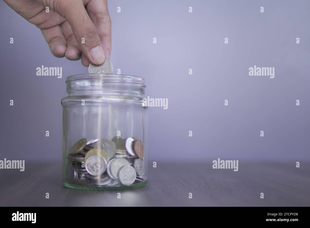 Main mettre une pièce dans un bocal en verre rempli de pièces. Copier l'espace pour le texte. Économiser de l'argent, concept de planification de la retraite. Banque D'Images