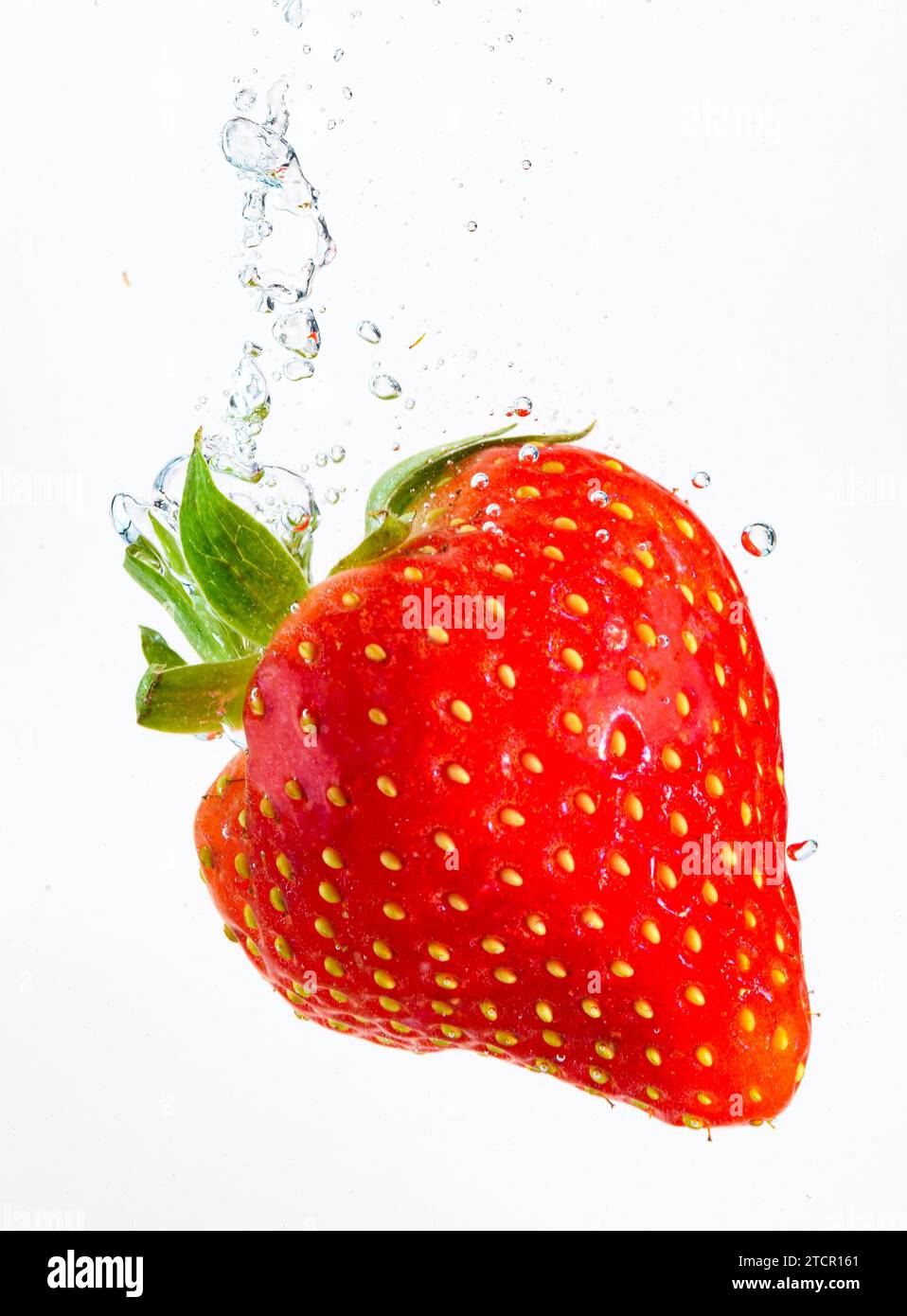 Strawberry tombe profondément sous l'eau avec un grand bruit. Naufrage de fruits dans l'eau claire sur fond blanc. Concept antioxydant Banque D'Images