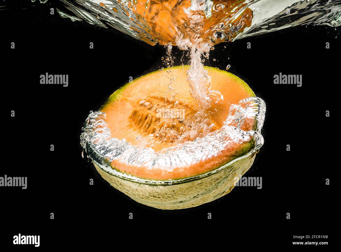 La moitié de la cantaloup orange coulant le melon, isolée sur fond noir Banque D'Images