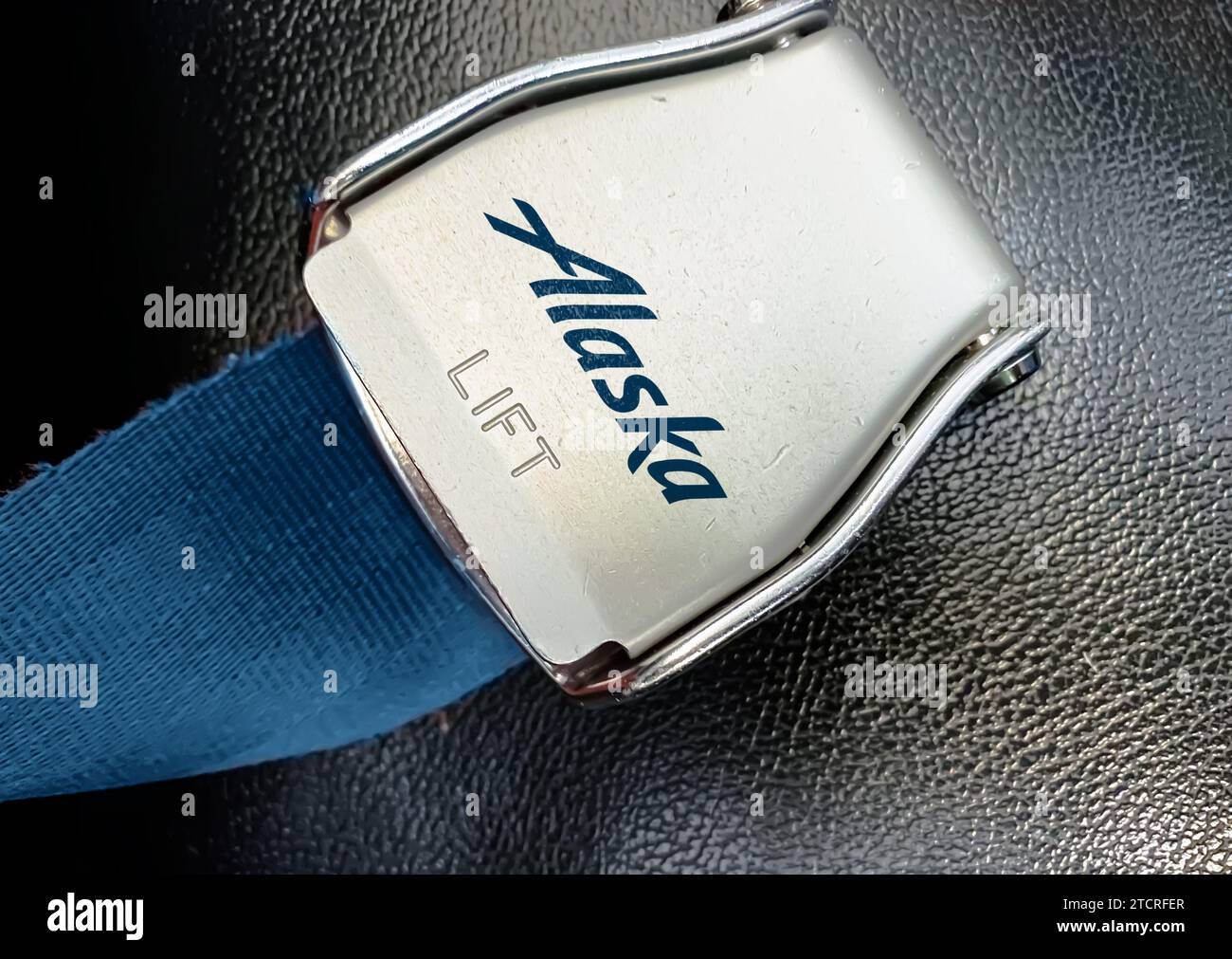 Anchorage, nov. 20 2023 : vue rapprochée d'une boucle de ceinture de sécurité métallique avec le logo Alaska Airlines sur un fond de tissu bleu avec un surf texturé Banque D'Images