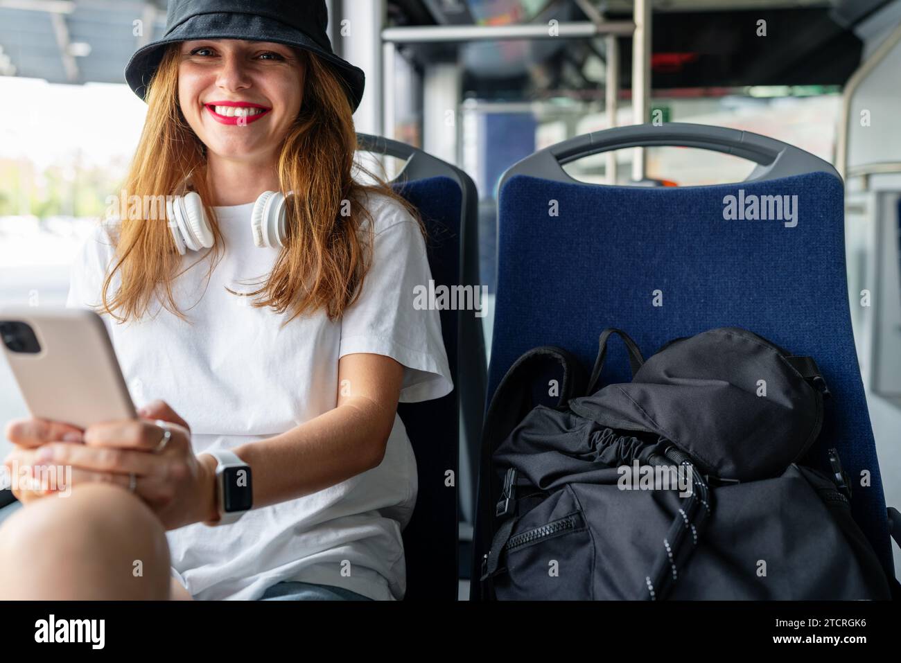 Jeune femme élégante sourit à l'intérieur du bus, embrassant le style de vie urbain. Ville commute Joy. Banque D'Images