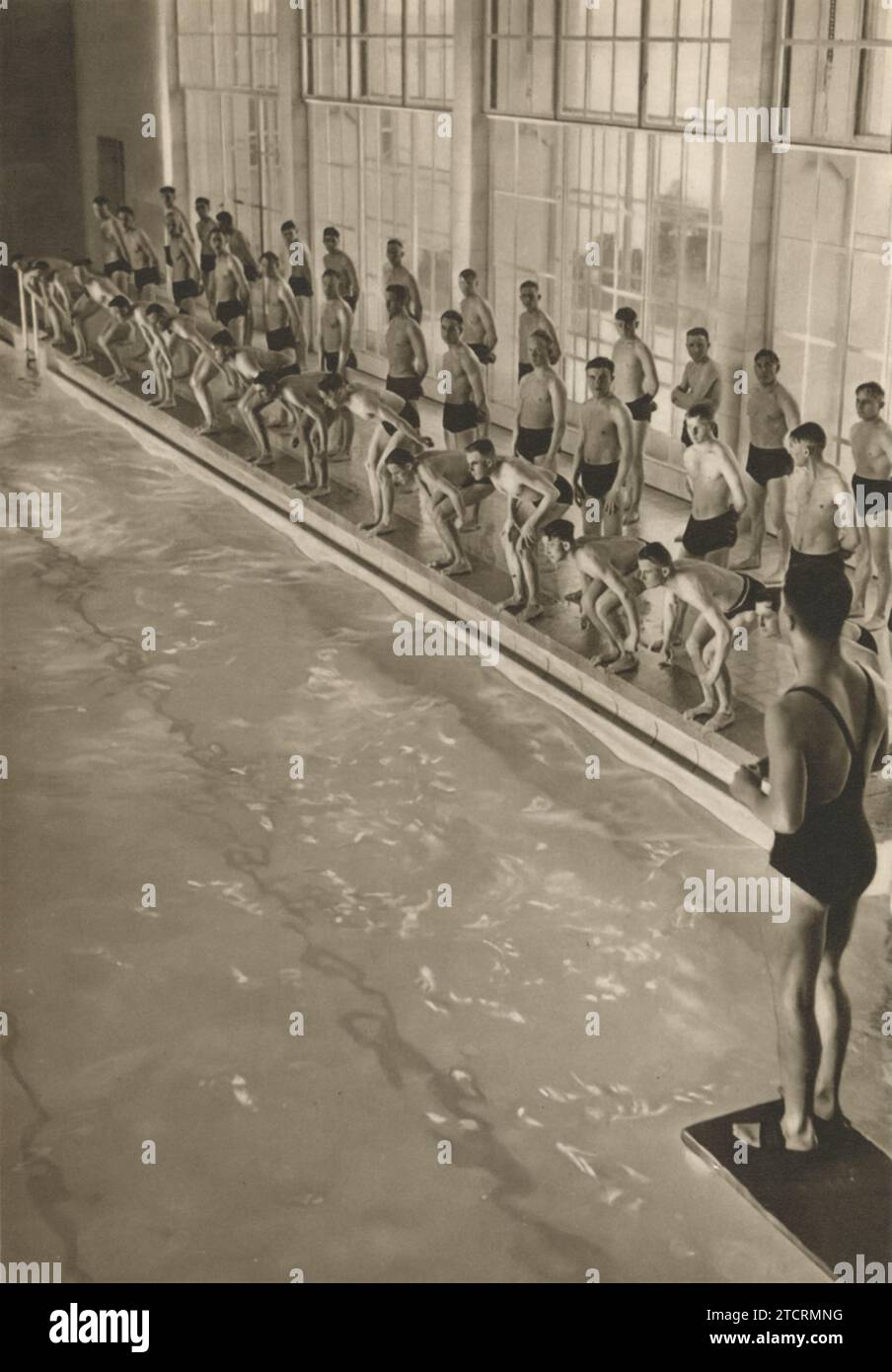 Les nouvelles recrues en formation militaire allemande sont montrées lors de leur séance sportive matinale, qui implique à cette occasion de nager. Cette activité rigoureuse fait partie de leur formation complète, les préparant probablement au service dans la Marine (Kriegsmarine). L'accent mis sur la natation met l'accent sur l'importance de la condition physique et des compétences spécialisées requises pour les opérations navales. Banque D'Images