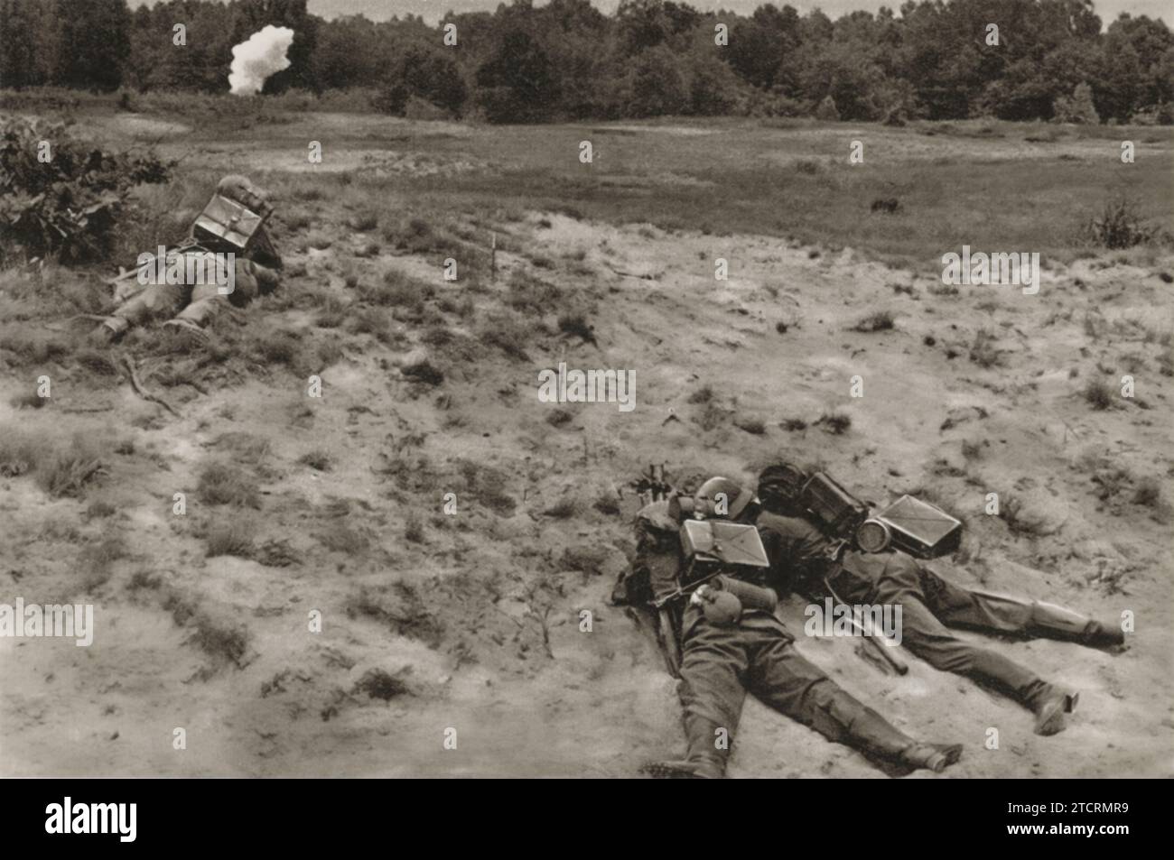 Trois recrues allemandes sont vues se mettre à couvert dans une tranchée, engagées dans un entraînement avec des grenades à bâton pendant leurs exercices militaires. Ce scénario leur enseigne les compétences vitales de l'utilisation de grenades tout en se couvrant pour la protection. Banque D'Images