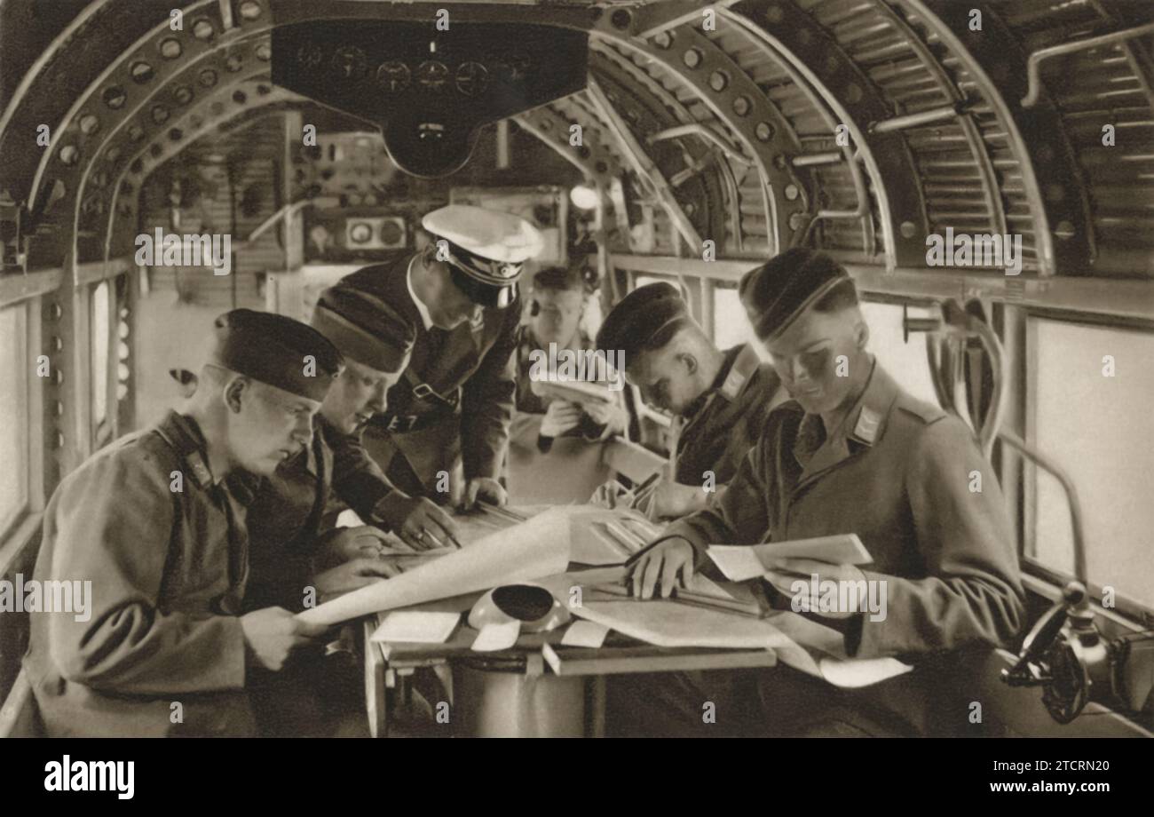 Sur cette image, les recrues allemandes de la Luftwaffe, l'armée de l'air allemande, sont représentées assises à l'intérieur d'un avion, engagées dans une session d'entraînement à la navigation. Cette partie de leur formation militaire était cruciale, car les compétences en navigation sont fondamentales pour tout pilote, en particulier dans le contexte de la guerre aérienne de la Seconde Guerre mondiale. Les recrues apprennent à lire et à interpréter divers instruments de navigation et cartes, compétences essentielles à la réussite de la planification et de l'exécution de la mission. Banque D'Images