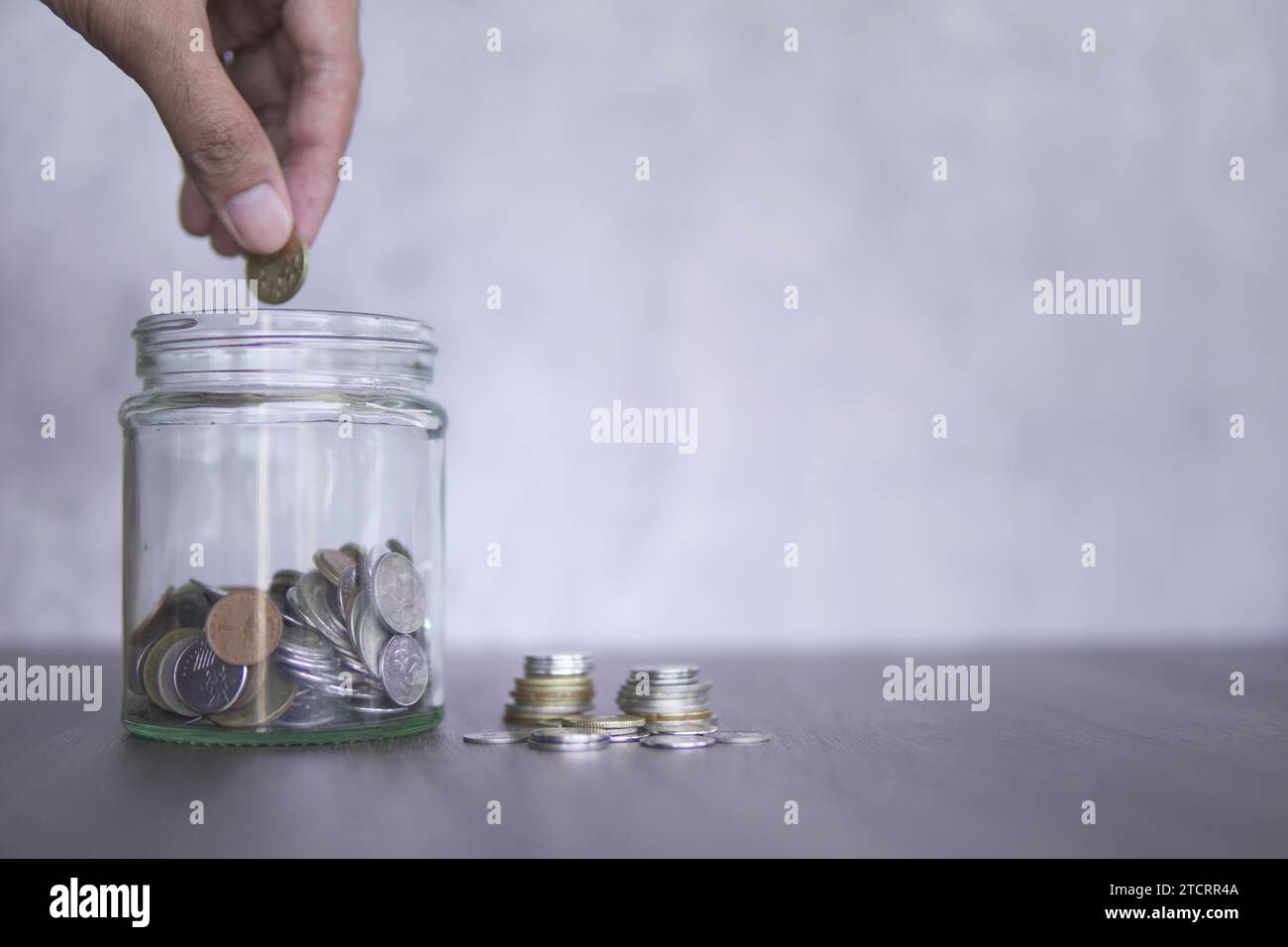 Main mettre une pièce dans un bocal en verre rempli de pièces. Copier l'espace pour le texte. Économiser de l'argent, concept de planification de la retraite. Banque D'Images