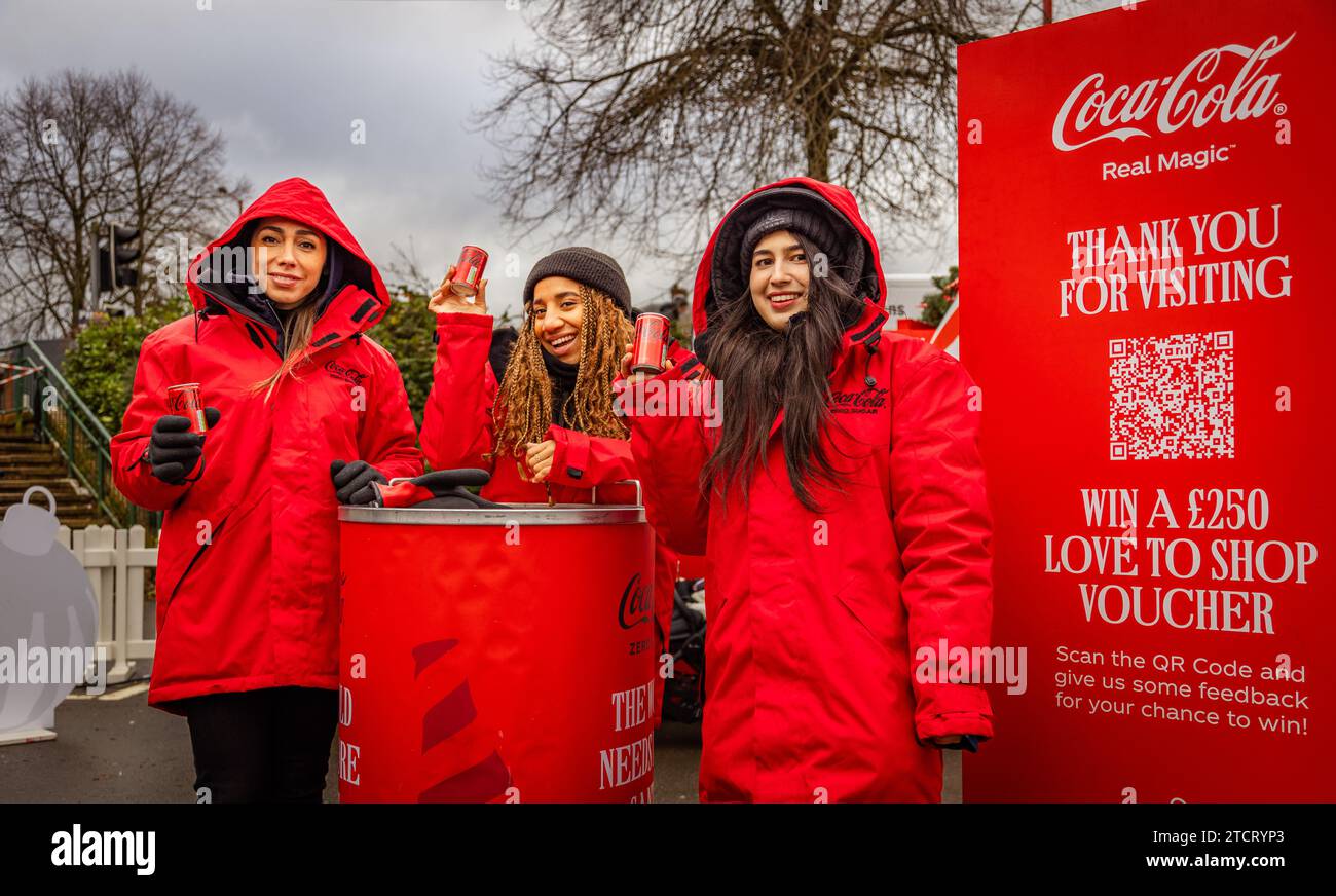 Promotions Coca Cola les filles lèvent une canette de la boisson emblématique à un arrêt pendant la tournée de Noël de Coca Cola en camion. Banque D'Images