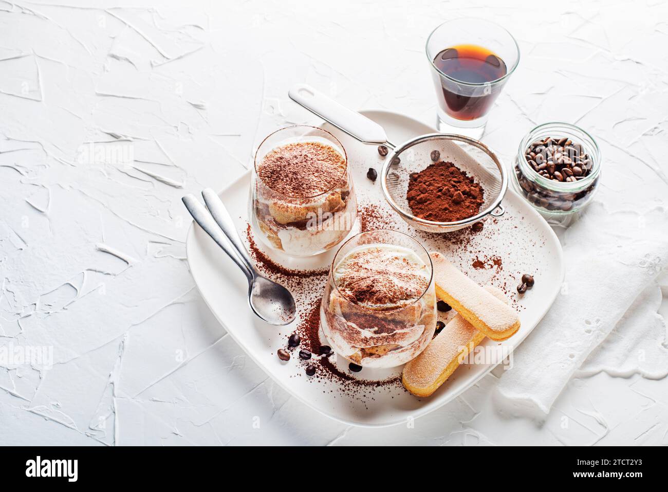 Dessert italien traditionnel tiramisu dans une tasse de verre. Tiramisu fait maison dans une tasse en verre, processus de cuisson étape par étape. Dessert italien traditionnel non cuit Banque D'Images