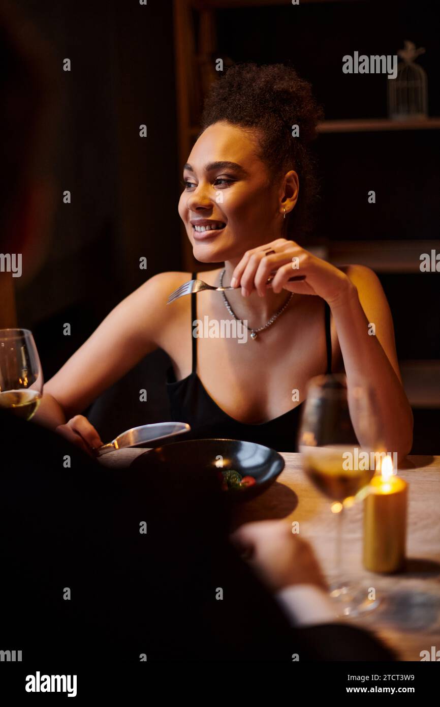 Joyeuse femme afro-américaine mangeant de la salade pendant la date avec petit ami dans le restaurant, Saint Valentin Banque D'Images