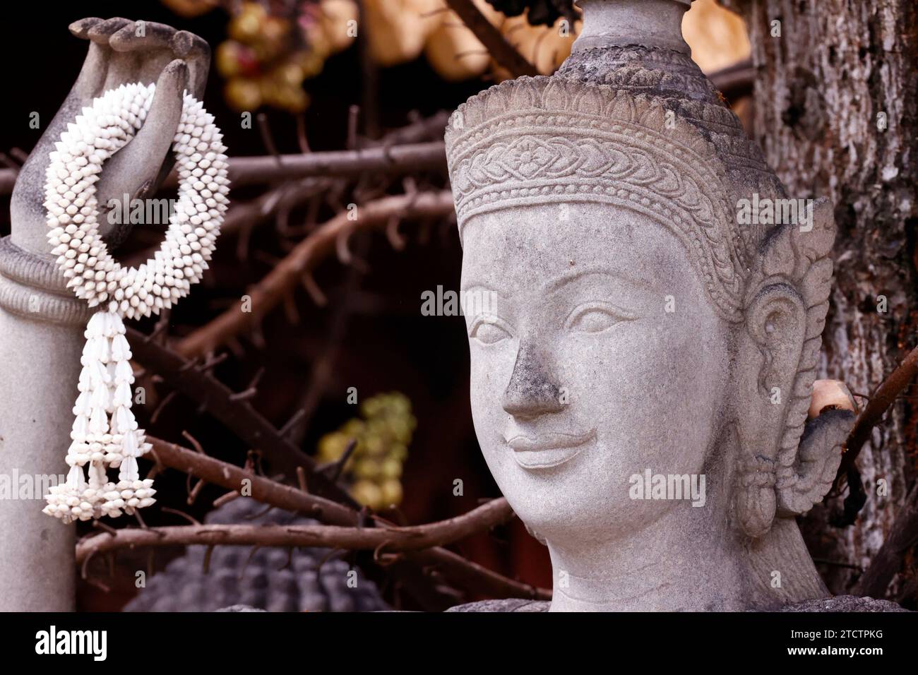 Statue de Bouddha en pierre avec des fleurs de jasmin dans les mains. Phnom Penh ; Cambodge. Banque D'Images