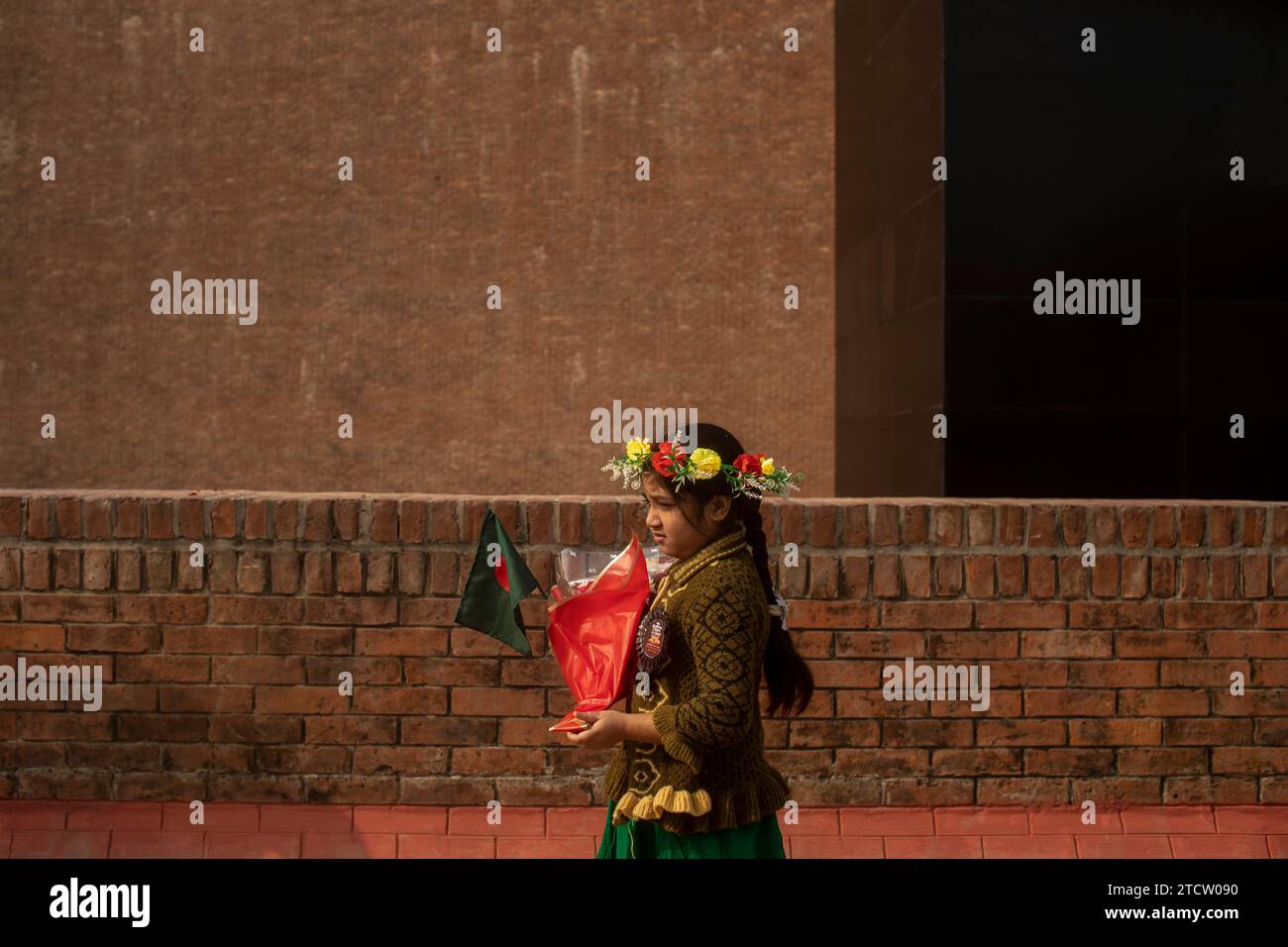 Dhaka, Bangladesh. 14 décembre 2023. Une fille tient des fleurs et un drapeau du Bangladesh pendant le Mémorial intellectuel des martyrs. Les Bangladeshis ont rendu hommage aux dizaines d'intellectuels tués pendant la guerre, qui a conduit au succès de l'indépendance du pays d'Asie du Sud vis-à-vis du Pakistan. Les intellectuels ont été systématiquement tués à travers l'ancien Pakistan oriental par l'armée pakistanaise et leurs collaborateurs pour mutiler la nation émergente de son peuple talentueux et intellectuel. (Photo de Sazzad Hossain/SOPA Images/Sipa USA) crédit : SIPA USA/Alamy Live News Banque D'Images