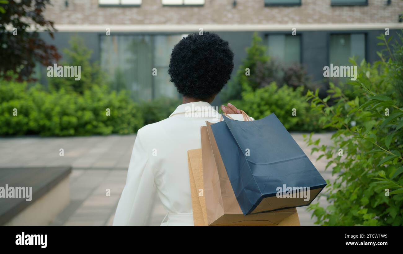 Vue arrière de derrière marchant dans la ville à l'extérieur femme afro-américaine tournant regardant la caméra heureuse souriante fille acheteur femme cliente dame Banque D'Images