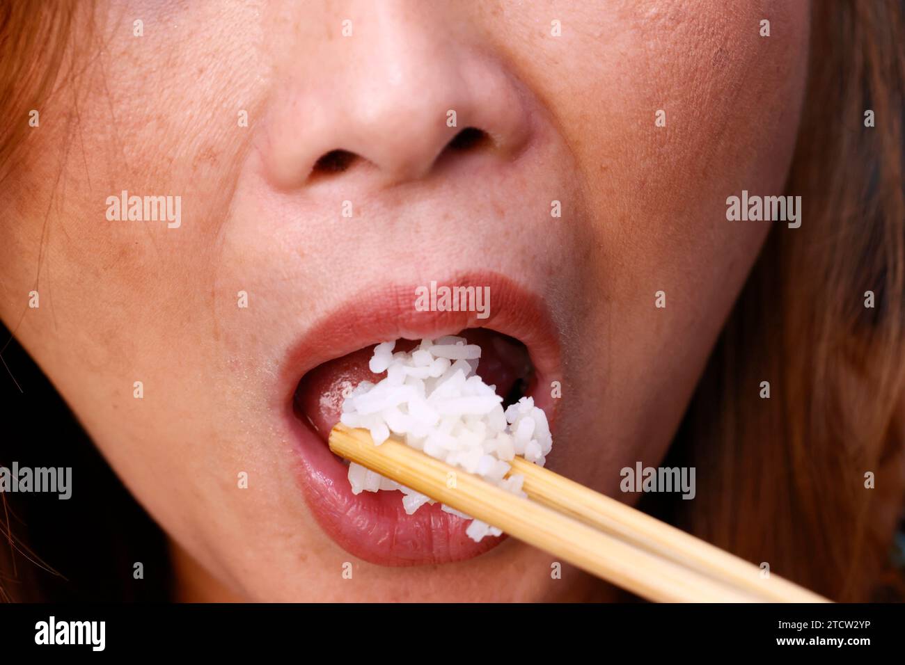 Femme mangeant du riz cuit à la vapeur. Gros plan sur les baguettes. Banque D'Images