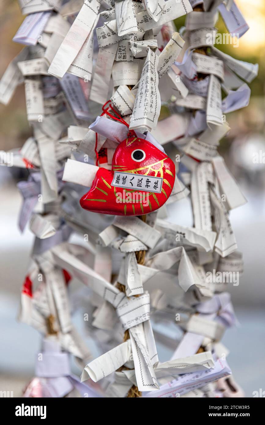 Poisson rouge et omikuji noués dans un temple japonais Banque D'Images