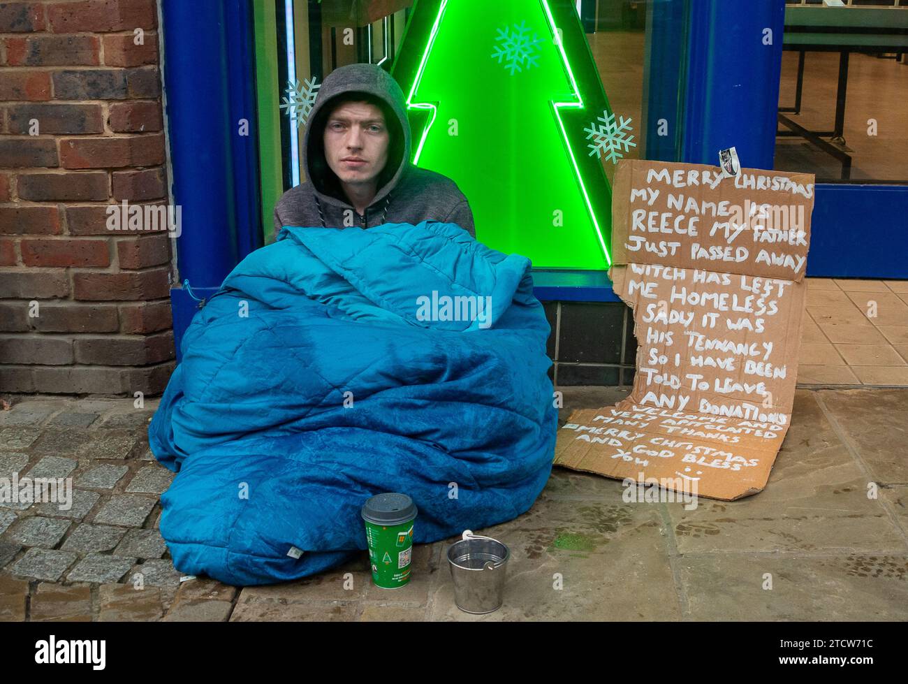 Windsor, Royaume-Uni. 14 décembre 2023. Reece, un homme qui a été rendu sans abri à la suite de la mort de son père, est assis sur le sol froid sous la pluie devant un magasin dans le riche Windsor, Berkshire, espérant que des passants lui donnent des pièces de monnaie. Polly Neate, directeur général de Shelter, a déclaré à Sky News que «le sans-abri n'est sur la liste de Noël de personne, mais 309 000 personnes passeront cette période de l'année dans une minuscule chambre d'auberge ou geler dans une porte». Crédit : Maureen McLean/Alamy Live News Banque D'Images Windsor, Royaume-Uni. 14 décembre 2023. Reece, un homme qui a été rendu sans abri à la suite de la mort de son père, est assis sur le sol froid sous la pluie devant un magasin dans le riche Windsor, Berkshire, espérant que des passants lui donnent des pièces de monnaie. Polly Neate, directeur général de Shelter, a déclaré à Sky News que «le sans-abri n'est sur la liste de Noël de personne, mais 309 000 personnes passeront cette période de l'année dans une minuscule chambre d'auberge ou geler dans une porte». Crédit : Maureen McLean/Alamy Live News Banque D'Images