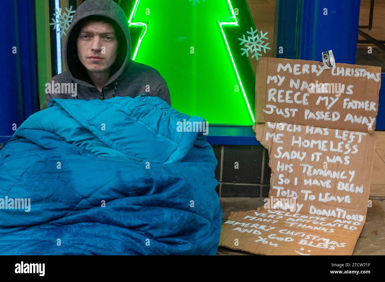 Windsor, Royaume-Uni. 14 décembre 2023. Reece, un homme qui a été rendu sans abri à la suite de la mort de son père, est assis sur le sol froid sous la pluie devant un magasin dans le riche Windsor, Berkshire, espérant que des passants lui donnent des pièces de monnaie. Polly Neate, directeur général de Shelter, a déclaré à Sky News que «le sans-abri n'est sur la liste de Noël de personne, mais 309 000 personnes passeront cette période de l'année dans une minuscule chambre d'auberge ou geler dans une porte». Crédit : Maureen McLean/Alamy Live News Banque D'Images Windsor, Royaume-Uni. 14 décembre 2023. Reece, un homme qui a été rendu sans abri à la suite de la mort de son père, est assis sur le sol froid sous la pluie devant un magasin dans le riche Windsor, Berkshire, espérant que des passants lui donnent des pièces de monnaie. Polly Neate, directeur général de Shelter, a déclaré à Sky News que «le sans-abri n'est sur la liste de Noël de personne, mais 309 000 personnes passeront cette période de l'année dans une minuscule chambre d'auberge ou geler dans une porte». Crédit : Maureen McLean/Alamy Live News Banque D'Images