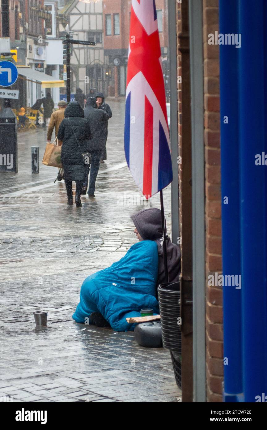 Windsor, Royaume-Uni. 14 décembre 2023. Reece, un homme qui a été rendu sans abri à la suite de la mort de son père, est assis sur le sol froid sous la pluie devant un magasin dans le riche Windsor, Berkshire, espérant que des passants lui donnent des pièces de monnaie. Polly Neate, directeur général de Shelter, a déclaré à Sky News que «le sans-abri n'est sur la liste de Noël de personne, mais 309 000 personnes passeront cette période de l'année dans une minuscule chambre d'auberge ou geler dans une porte». Crédit : Maureen McLean/Alamy Live News Banque D'Images Windsor, Royaume-Uni. 14 décembre 2023. Reece, un homme qui a été rendu sans abri à la suite de la mort de son père, est assis sur le sol froid sous la pluie devant un magasin dans le riche Windsor, Berkshire, espérant que des passants lui donnent des pièces de monnaie. Polly Neate, directeur général de Shelter, a déclaré à Sky News que «le sans-abri n'est sur la liste de Noël de personne, mais 309 000 personnes passeront cette période de l'année dans une minuscule chambre d'auberge ou geler dans une porte». Crédit : Maureen McLean/Alamy Live News Banque D'Images