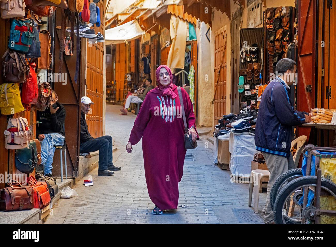 Femme musulmane marocaine portant djellaba / jillaba et hijab dans une ruelle avec des magasins dans la médina de la ville de Fès / Fès, Fès-Meknès, Maroc Banque D'Images